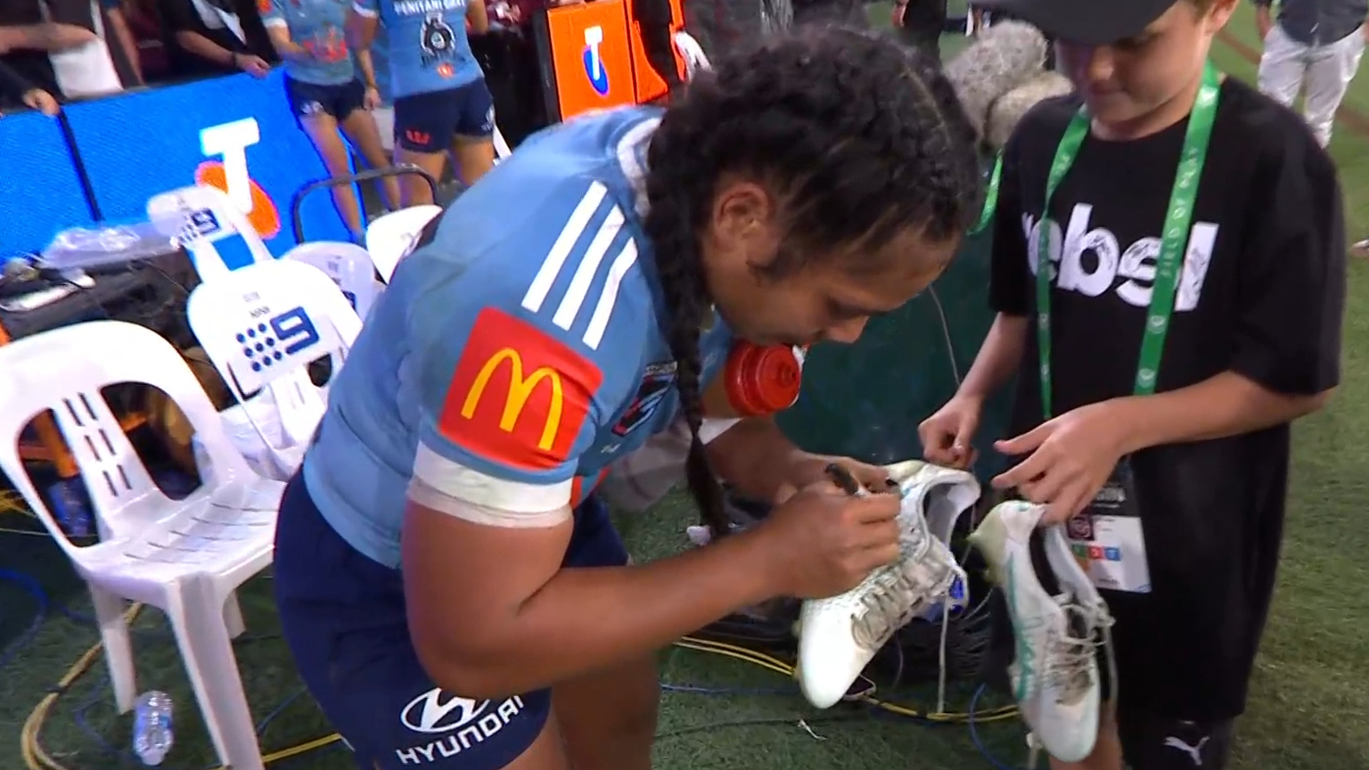 Simaima Taufa signs and gifts her boots to a young boy at Suncorp Stadium.