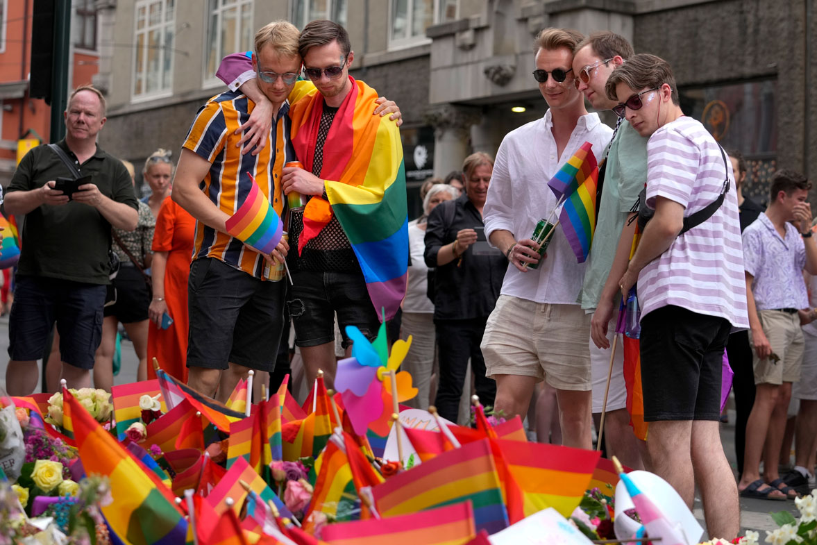 People react as they lay flowers at the scene of a shooting in central Oslo, Norway, Saturday, June 25, 2022.