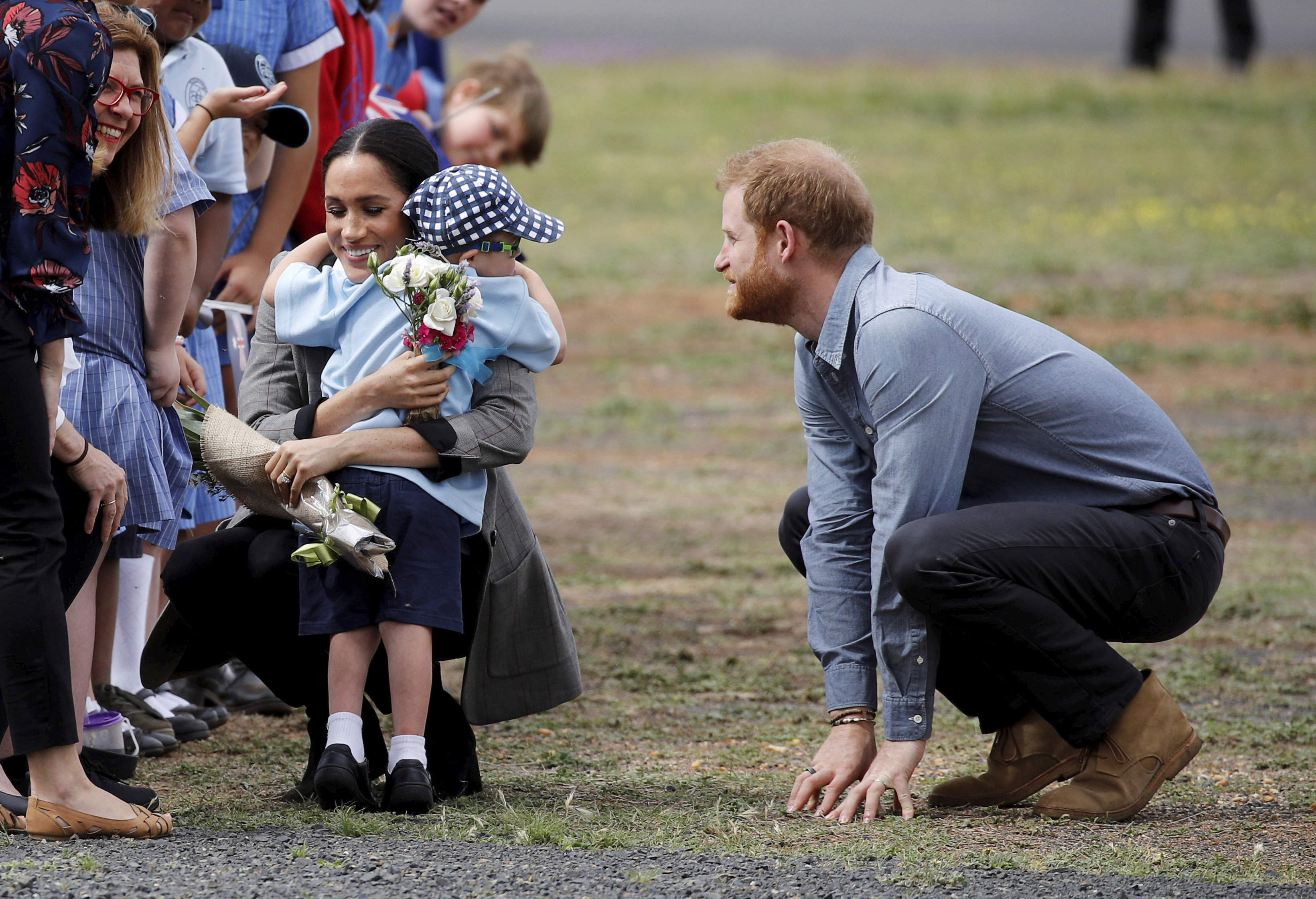 Prince Harry and Meghan, Duchess of Sussex are embraced by Luke Vincent, 5, on their arrival in Dubbo, Australia, Wednesday, Oct. 17, 2018. 
