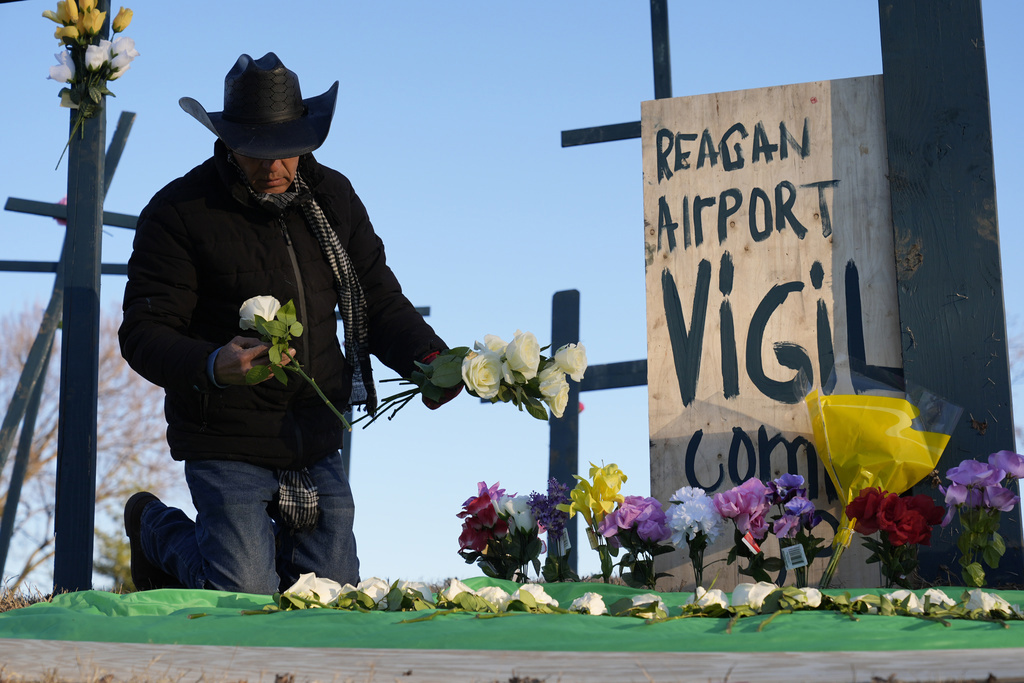 Roberto Márquez, de Dallas, coloca flores en un monumento para las 67 víctimas de una colisión en el aire entre un helicóptero del ejército y un vuelo de American Airlines desde Kansas cerca del Aeropuerto Nacional Ronald Reagan Washington.