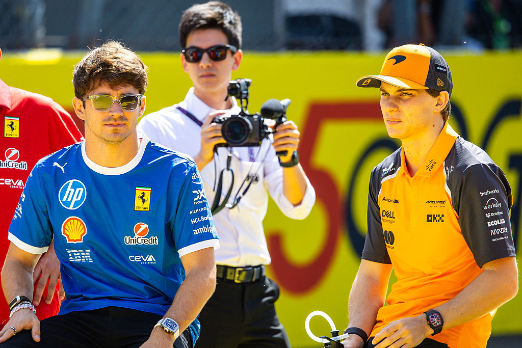 Oscar Piastri looks on from the pit lane with Charles Leclerc.