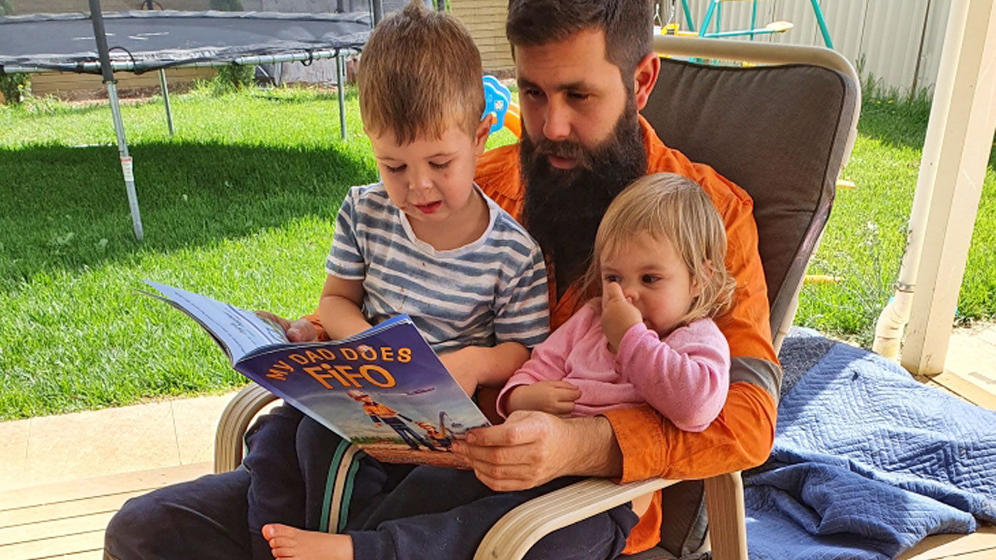 Craig Tarca, pictured with his son Charlie and daughter Ellen on the day before he left in March. He is reading a FIFO book explaining why he will be away for an extra long time.