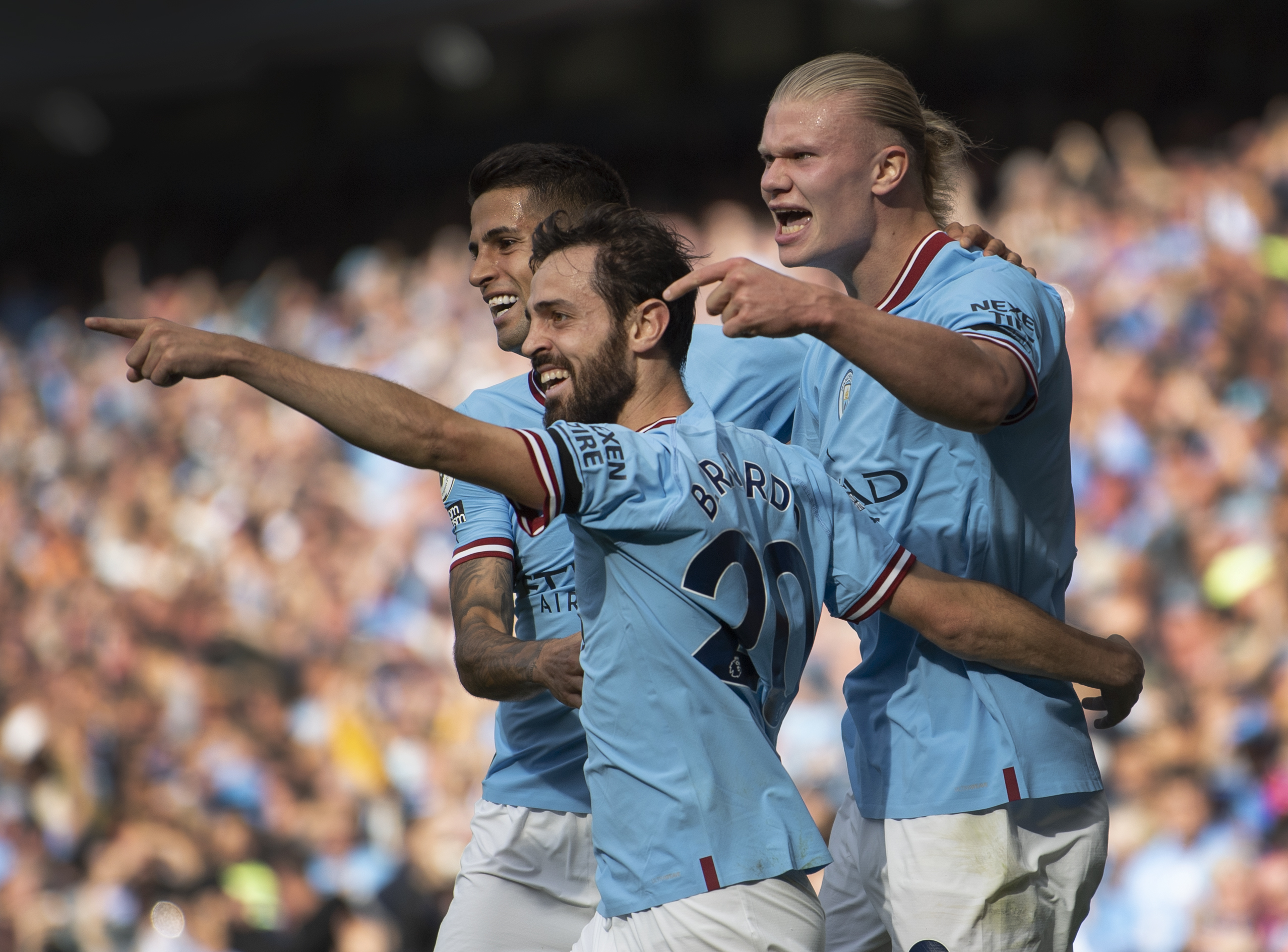 Erling Haaland of Manchester City celebrates scoring his second goal of a hat trick with teammates Joao Cancelo and Bernardo Silva.