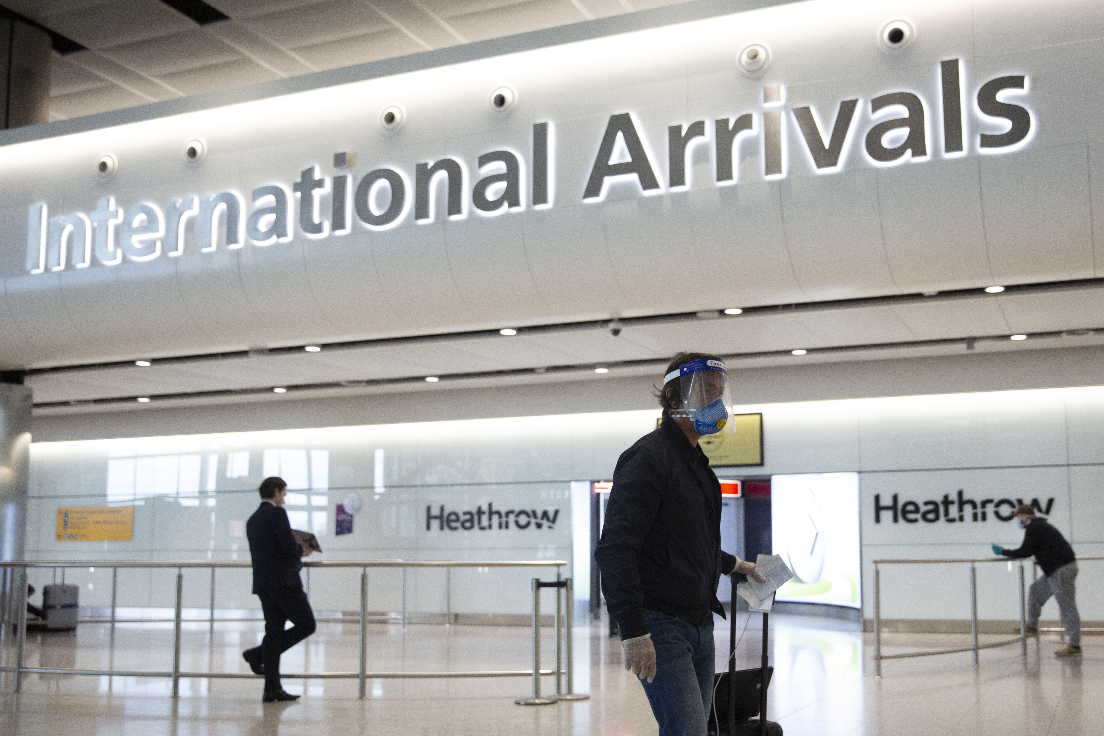 A passenger wearing a face shield and face mask arrives on the first day of new rules that people arriving in Britain from overseas will have to quarantine themselves for 14 days to help stop the spread of coronavirus, at Heathrow Airport in London, Monday, June 8, 2020. The British government has said that anyone caught not complying with the quarantine will face a fine. (AP Photo/Matt Dunham)