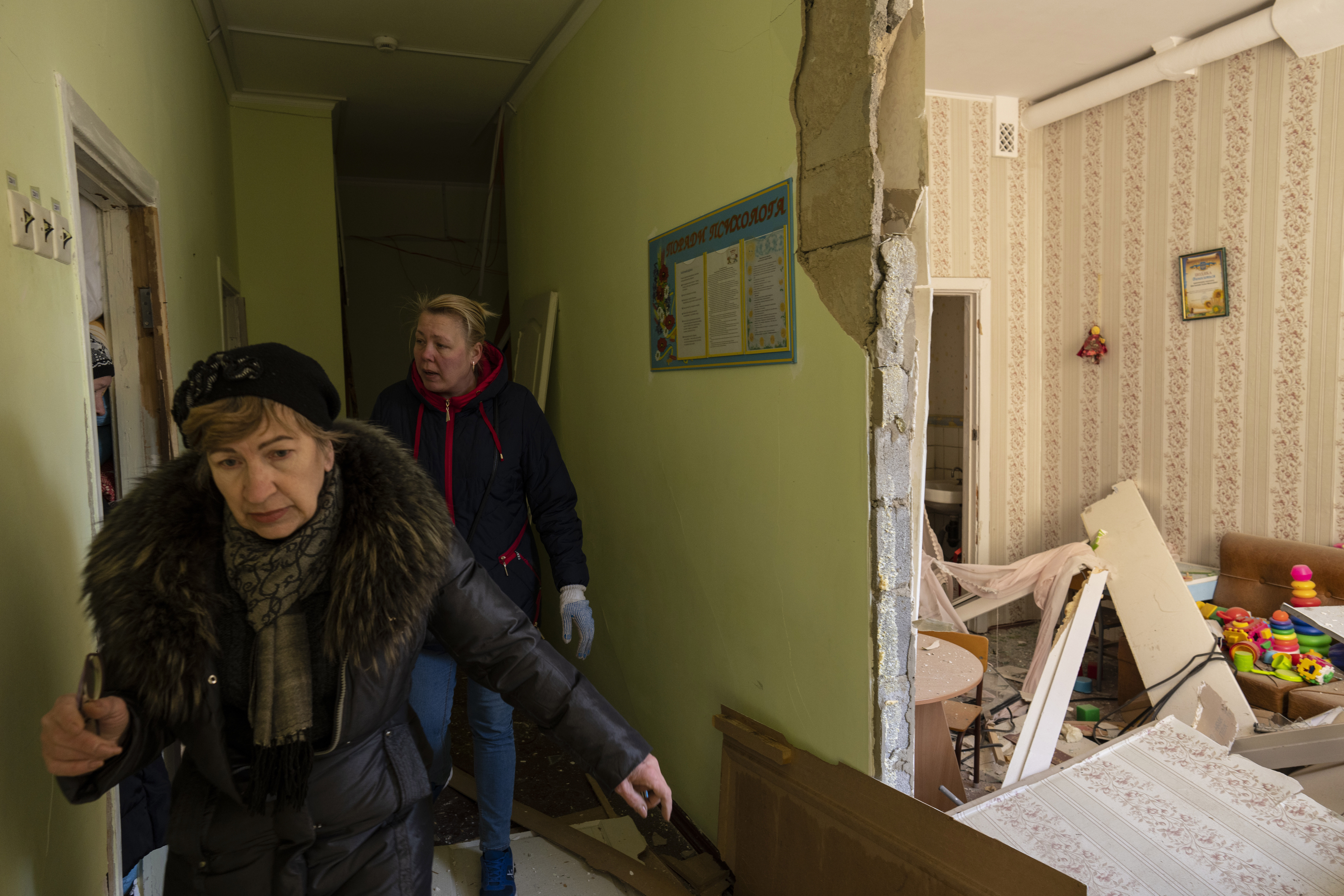 Women walks inside a school damaged among other residential buildings following a bombing in Kyiv, Ukraine, Friday, March 18, 2022. 