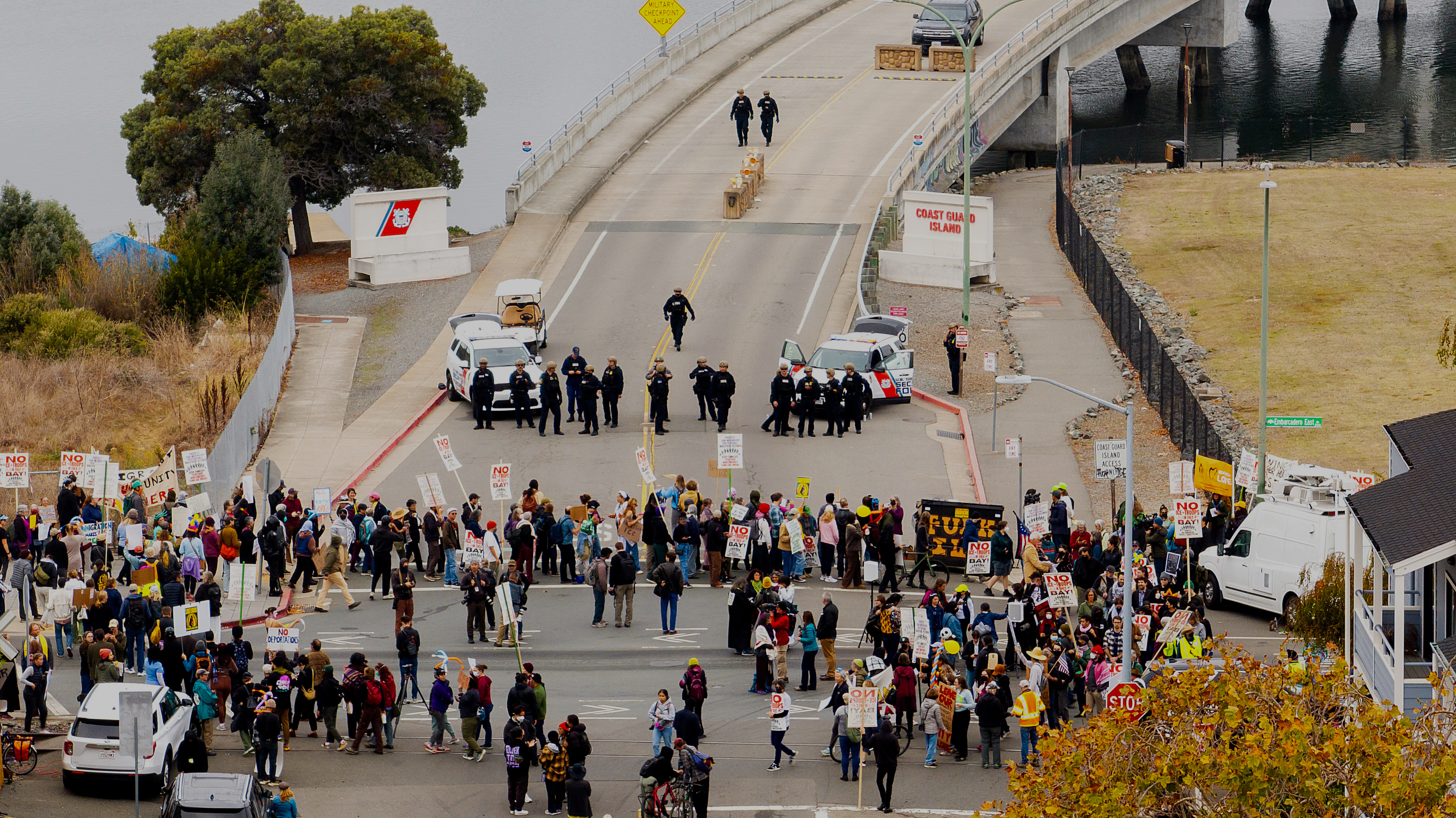 EDS NOTE: OBSCENITY - Protesters block the entrance to Coast Guard Base Alameda shortly after a caravan of U.S. Customs and Border Protection personnel arrived on Thursday, Oct. 23, 2025, in Oakland, Calif. (AP Photo/Noah Berger)