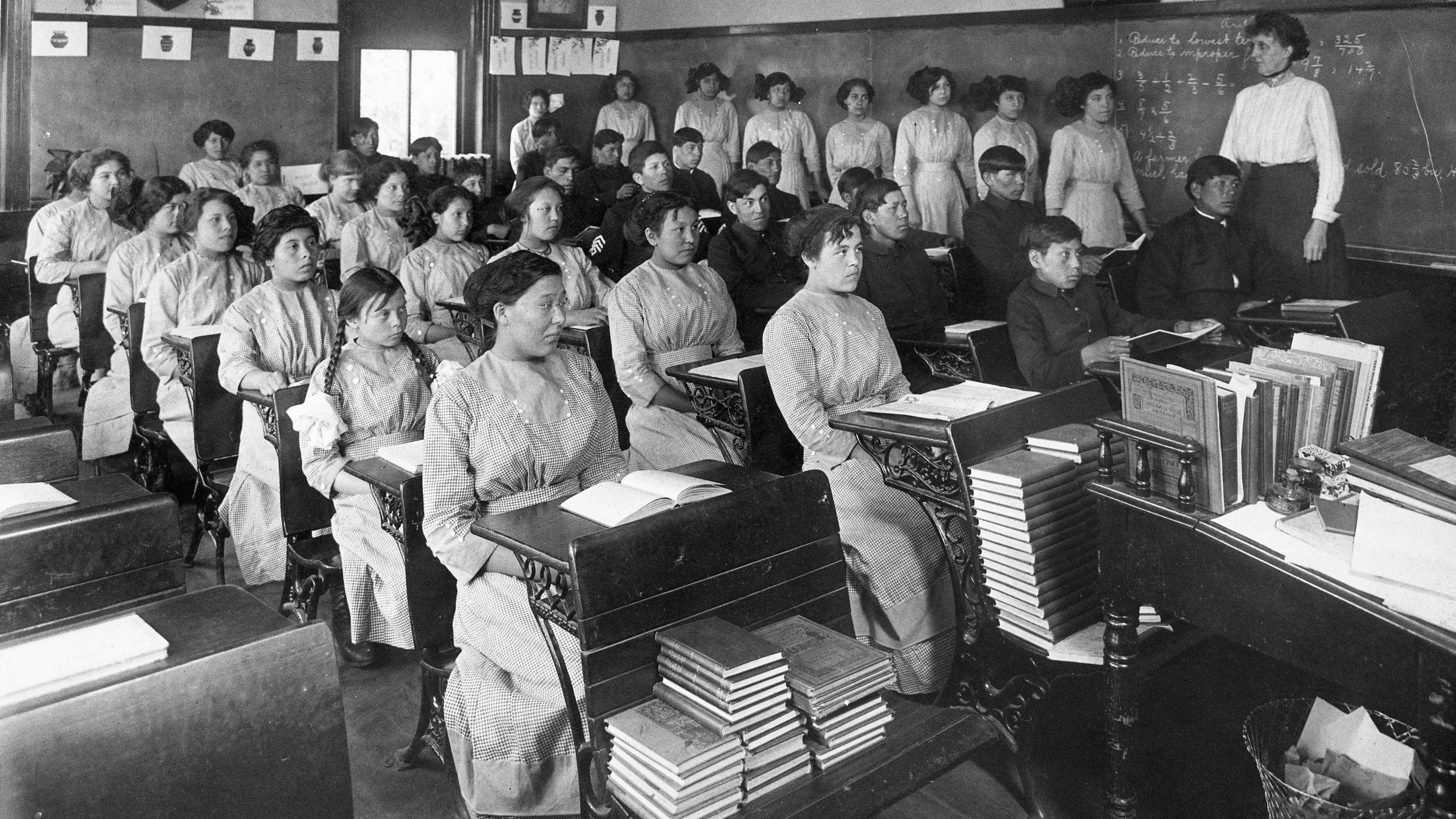 En esta foto sin fecha proporcionada por los Archivos Nacionales, los estudiantes de cuarto grado se sientan en un salón de clases en la antigua Escuela Industrial India de Génova en Génova, Nebraska, EE. UU.