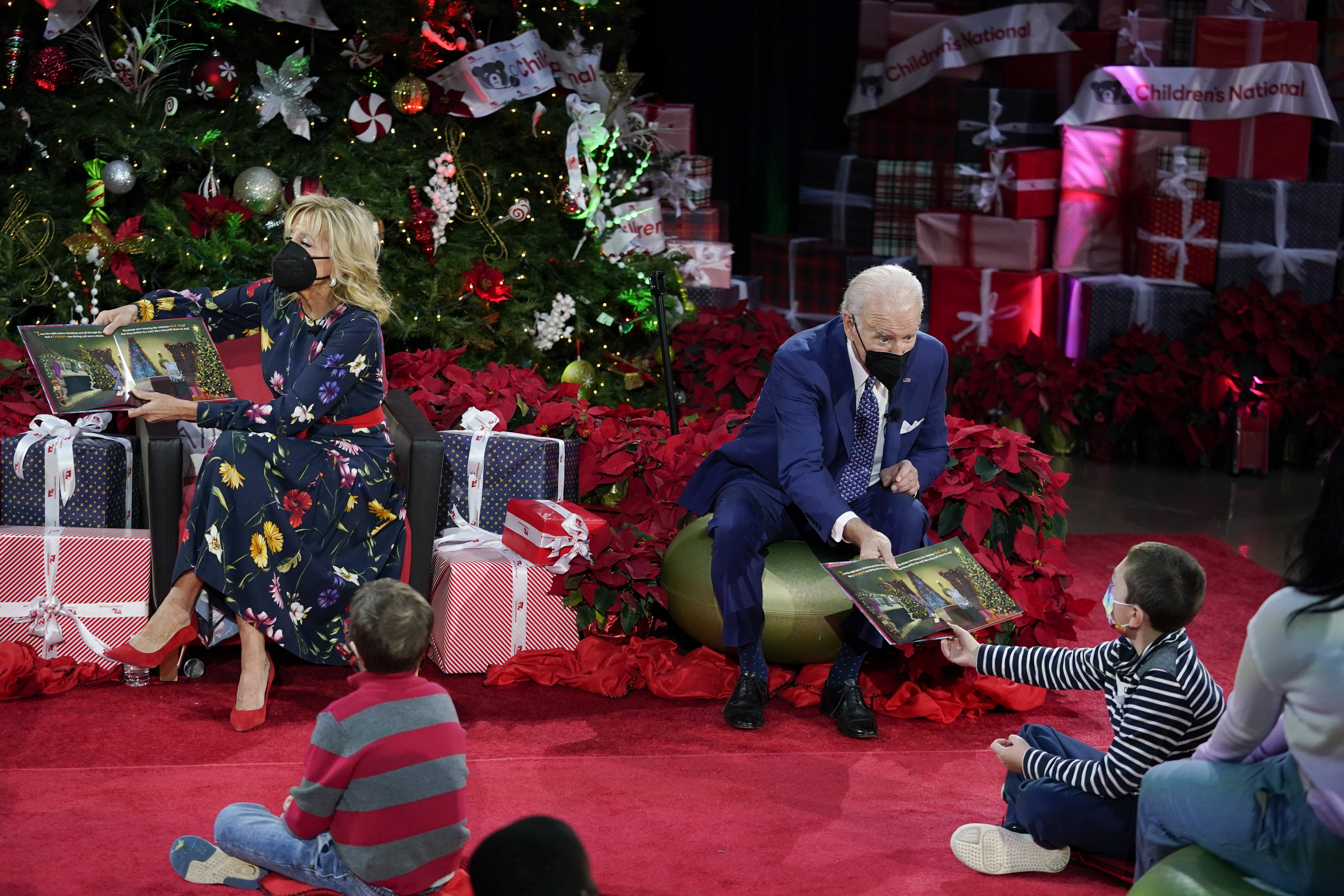 President Joe Biden hands a copy of a "Olaf's Night Before Christmas" to a child as first lady Jill Biden reads aloud at Children's National Hospital in Washington, Friday, Dec. 24, 2021. 