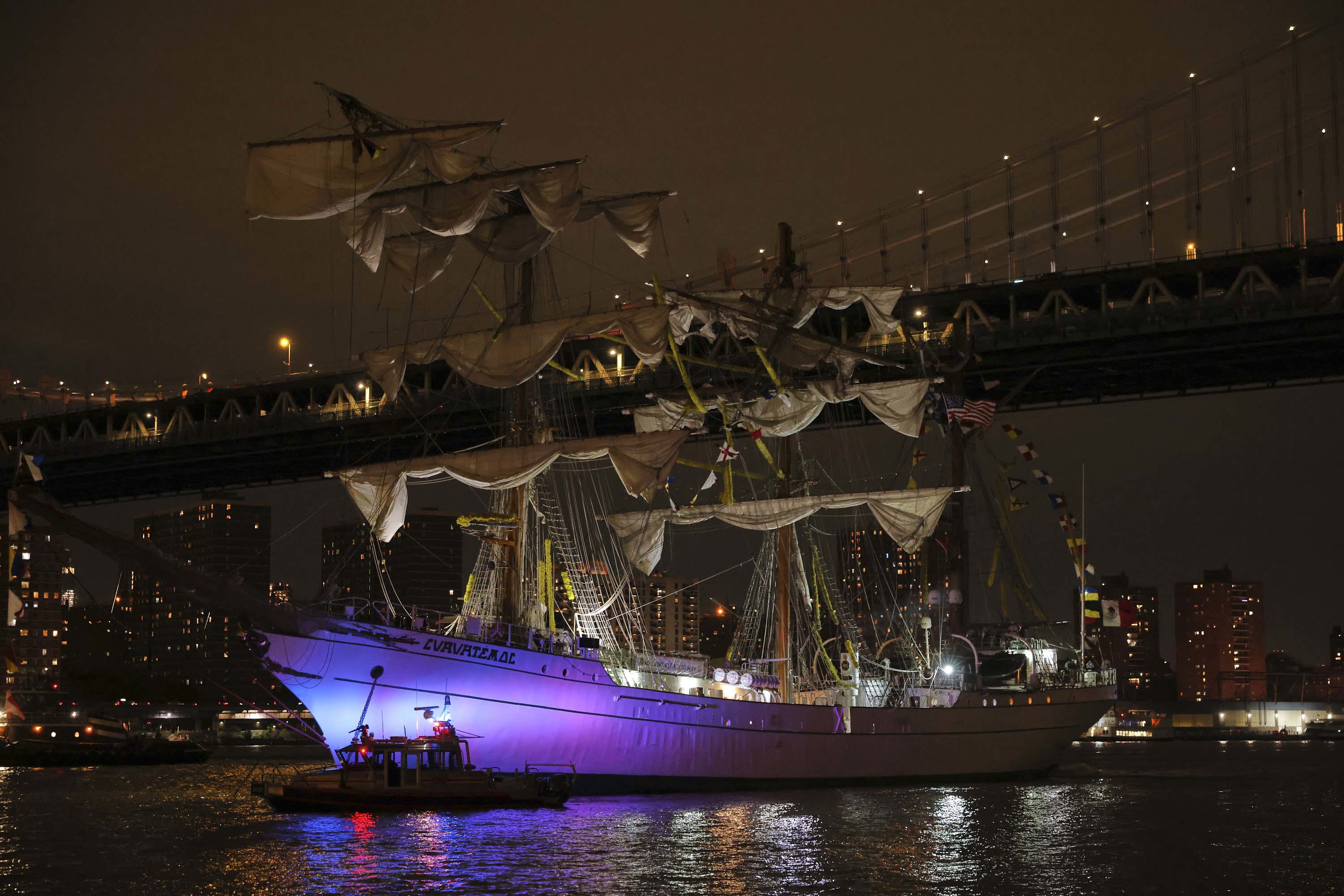 A New York Police Department harbor unit passes in front of the Cuauhtémoc, a masted Mexican Navy training ship as it sits stranded near the Manhattan Bridge after colliding with the Brooklyn Bridge.