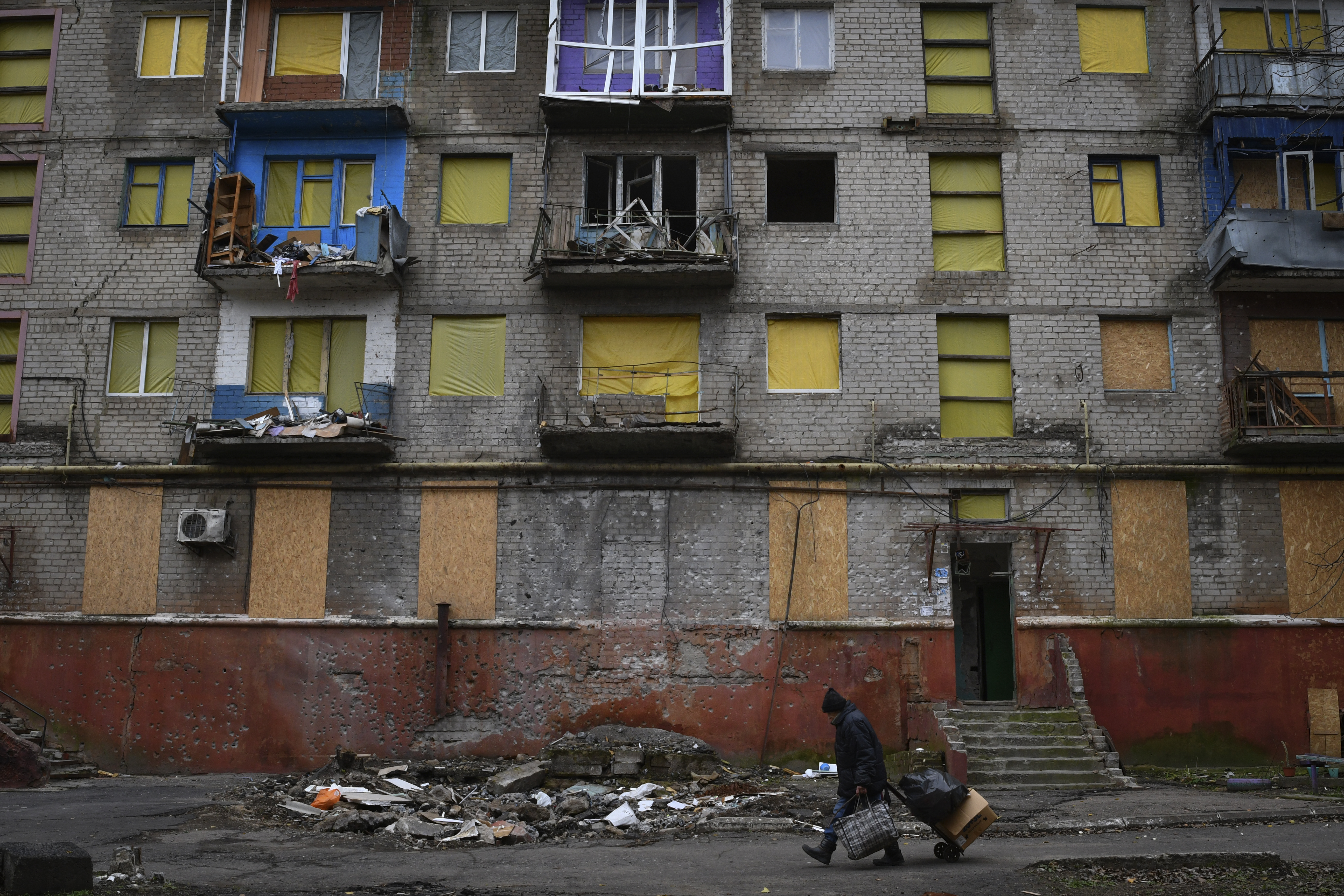 A man with a cart passes a building damaged by shelling in Kramatorsk, Ukraine, Friday, November 11, 2022. 