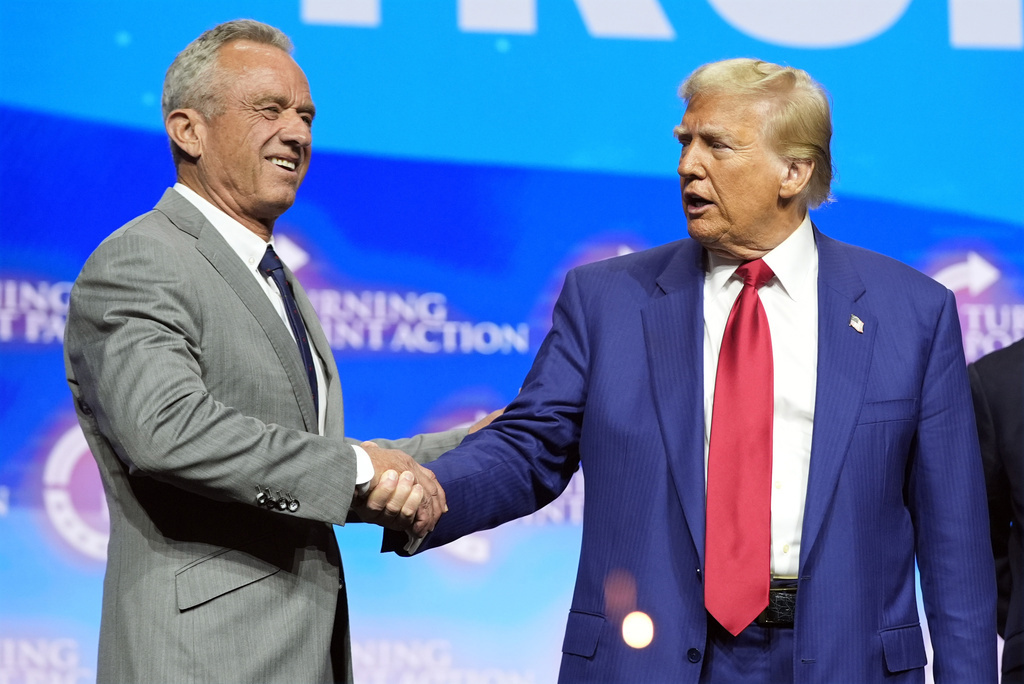 Republican presidential nominee former President Donald Trump shakes hands with Robert F. Kennedy Jr.