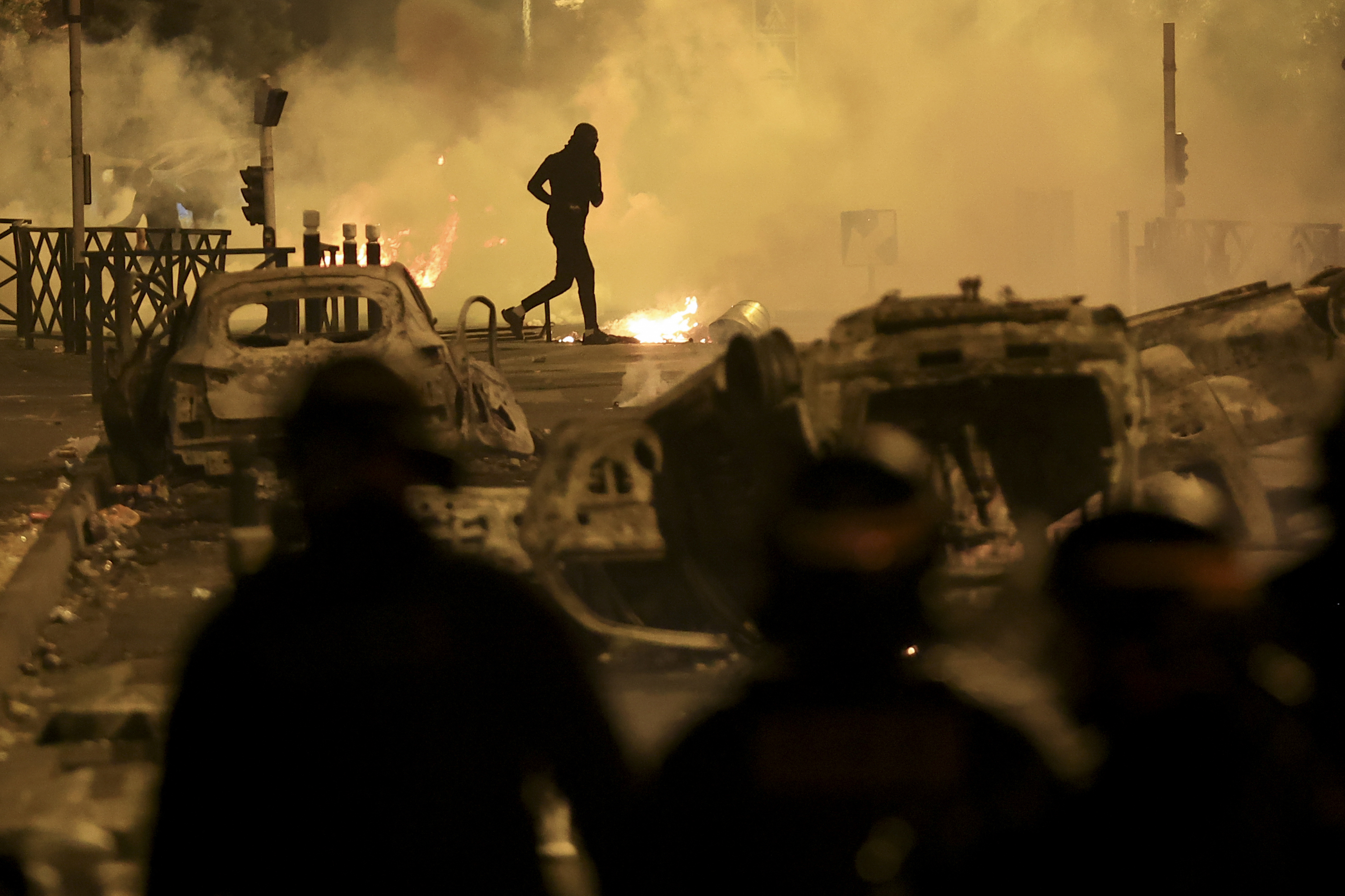 A demonstrator runs on the third night of protests sparked by the fatal police shooting of a 17-year-old driver in the Paris suburb of Nanterre, France, Friday, June 30, 2023. 
