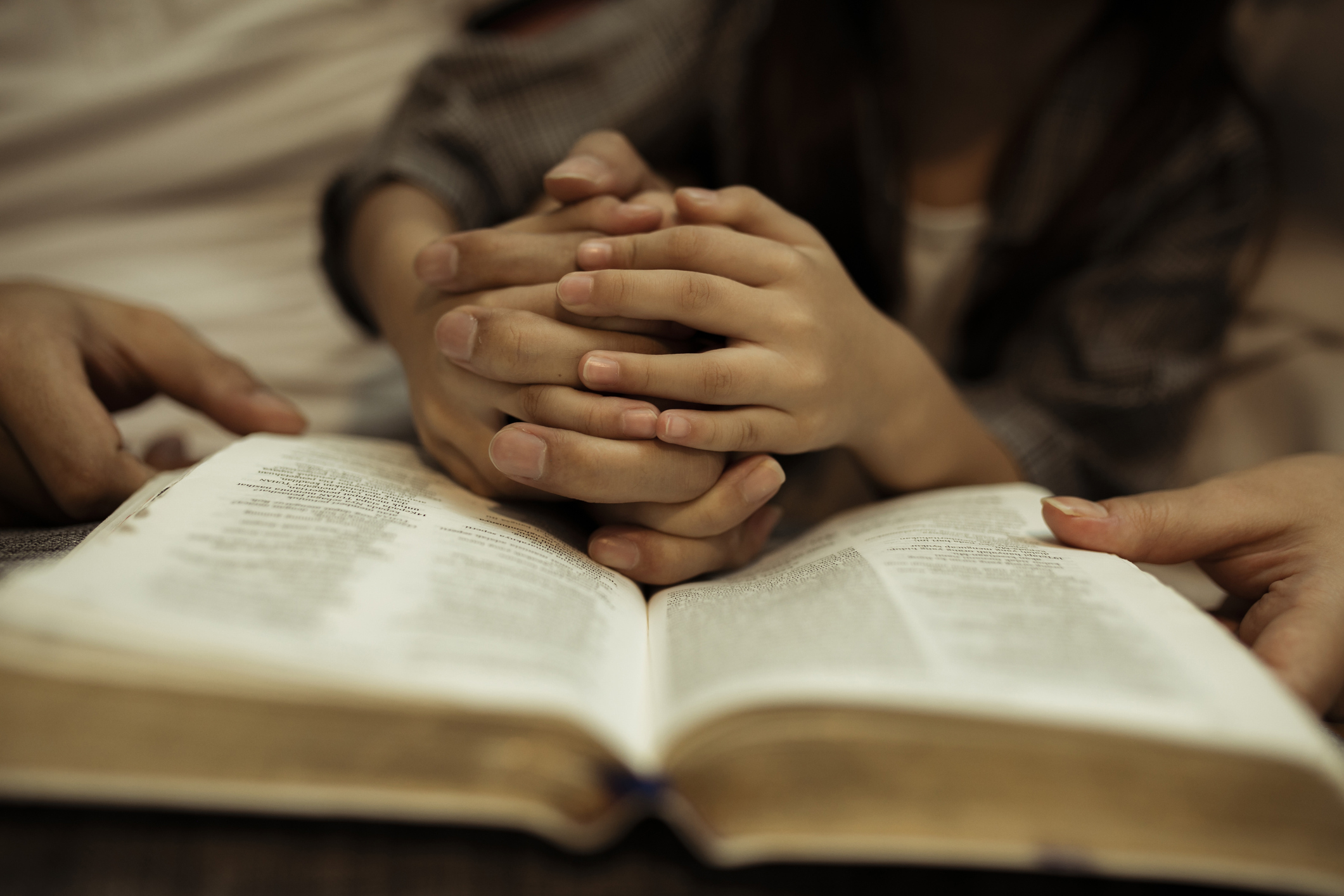 a kid reading the holy bible with guide by parents
