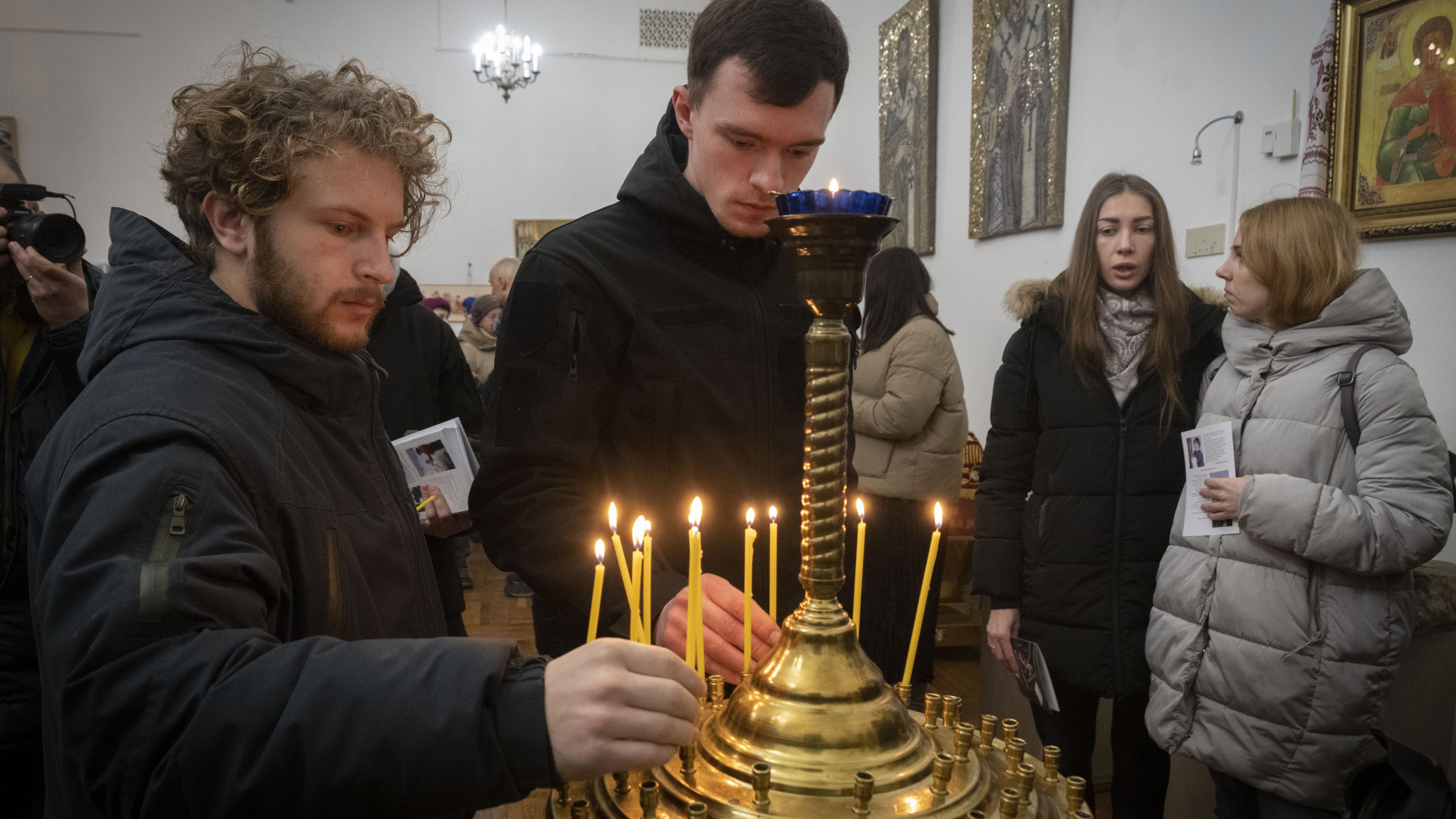 People light candles to commemorate British volunteers Chris Parry and Andrew Bagshaw, killed in Ukraine's war-hit east, during commemorating service in a refectory near St. Sophia Cathedral in Kyiv, Ukraine.