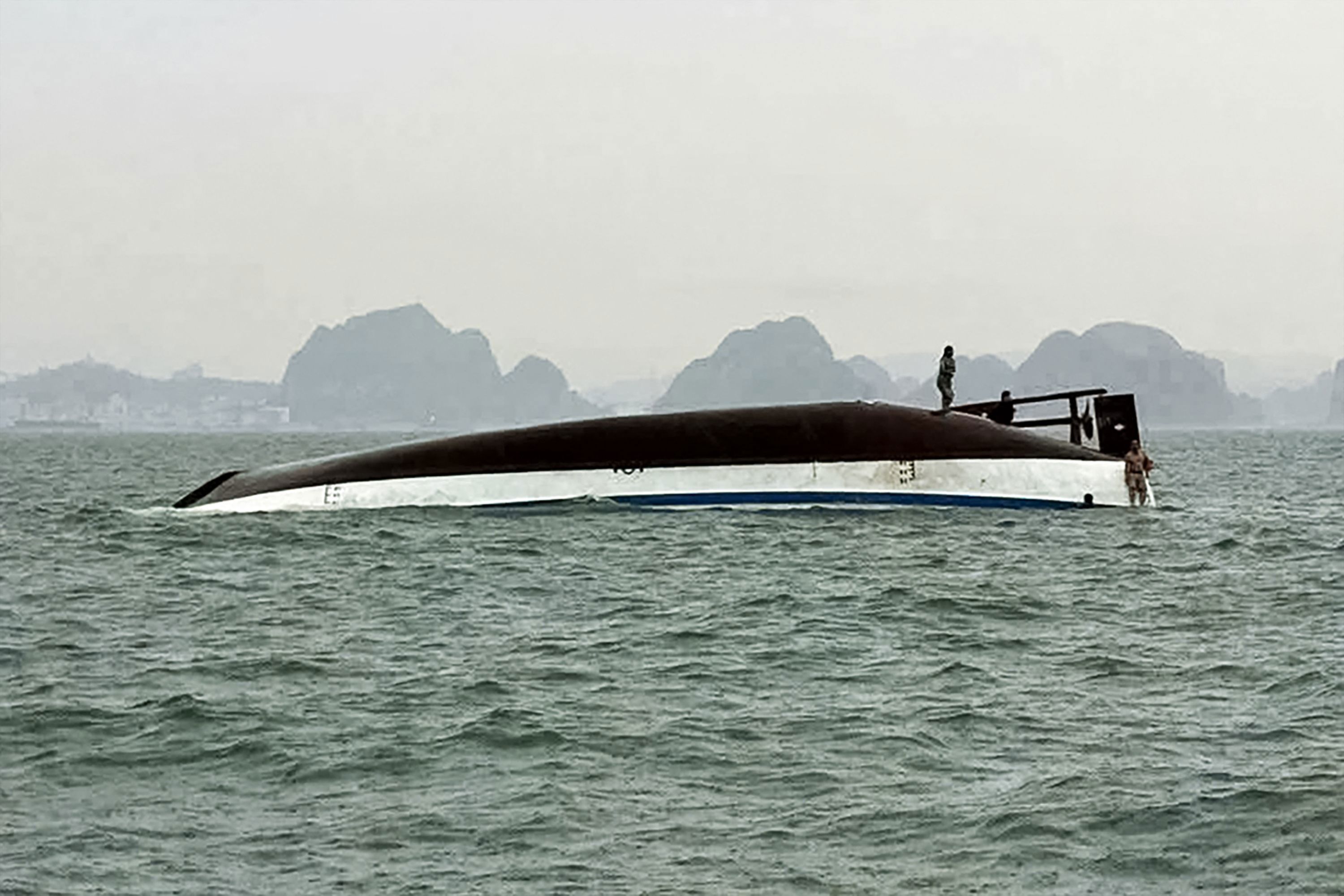 People stand on a tourist boat that capsized in Halong Bay on Saturday.
