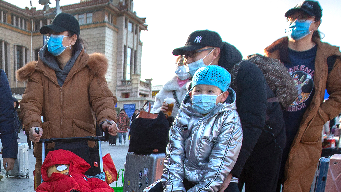 Travellers wear face masks as they walk outside of the Beijing Railway Station. China has reported a sharp rise in the number of people infected with a new coronavirus, including the first cases in the capital.