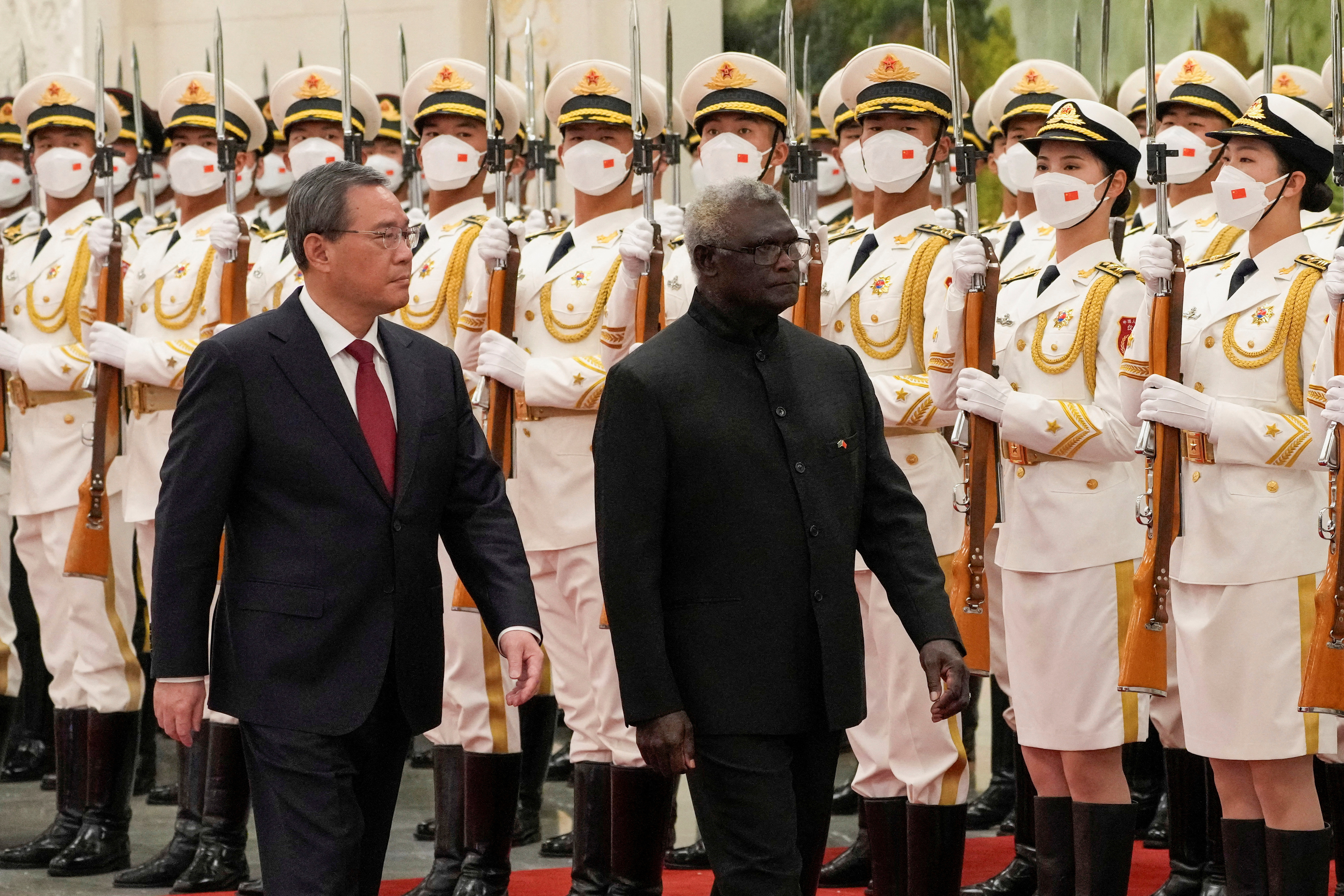 El primer ministro visitante de las Islas Salomón, Manasseh Sogavare, a la derecha, y su homólogo chino, Li Qiang, pasan revista a una guardia de honor durante una ceremonia de bienvenida en el Gran Salón del Pueblo en Beijing, el lunes 10 de julio de 2023.  