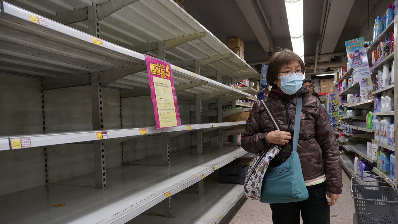 A woman wearing face mask walks past empty shelf of tissue papers at supermarket in Hong Kong, Thursday, Feb. 6, 2020