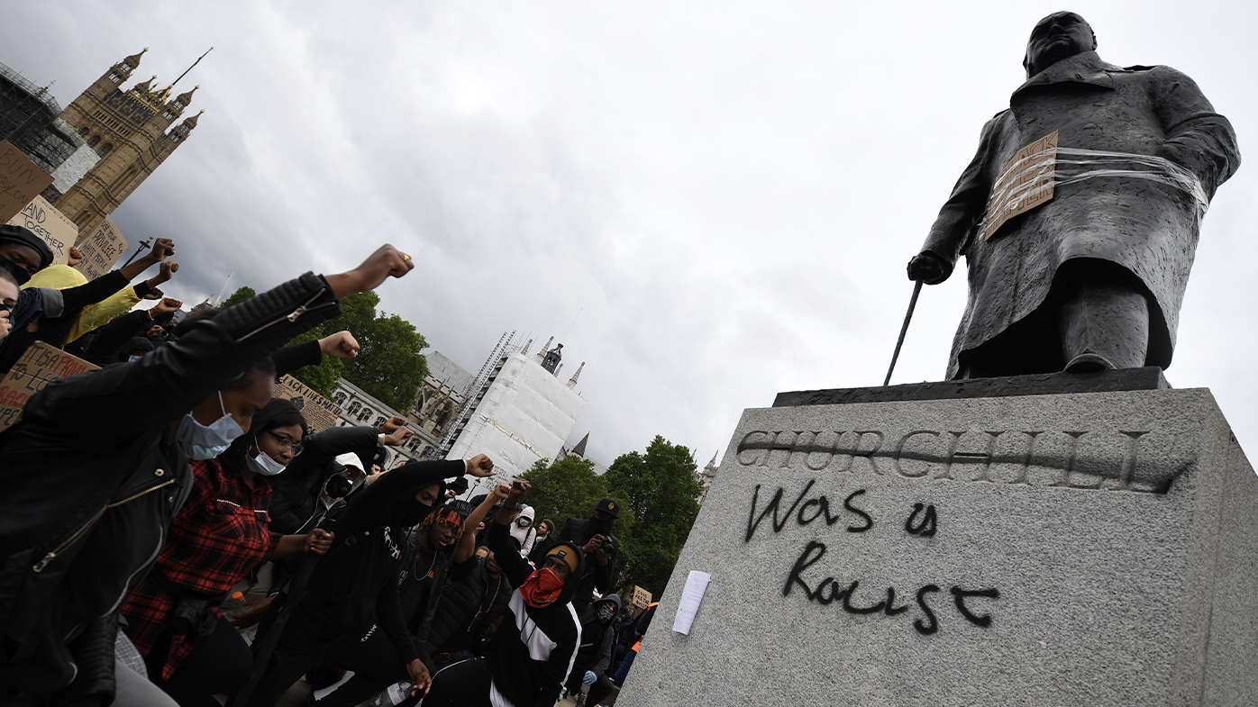 Protesters raise their fists in Parliament Square Garden around the statue of Winston Churchill which has graffiti with the words "was a racist" outside the Houses of Parliament in Westminster during a Black Lives Matter protest on June 07, 2020 in London, United Kingdom. 
