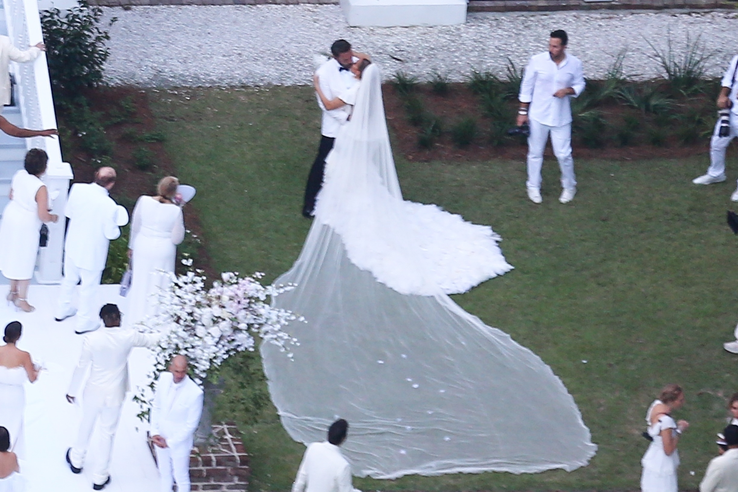 Jennifer Lopez wears a stunning white wedding dress as she celebrates her marriage to Ben Affleck, suitably dashing in a white jacket and black pants. The couple kissed and posed for pics around Bens $8million Georgia mansion on Saturday evening before spending the night celebrating their love and their union with family and a raft of A-list friends.