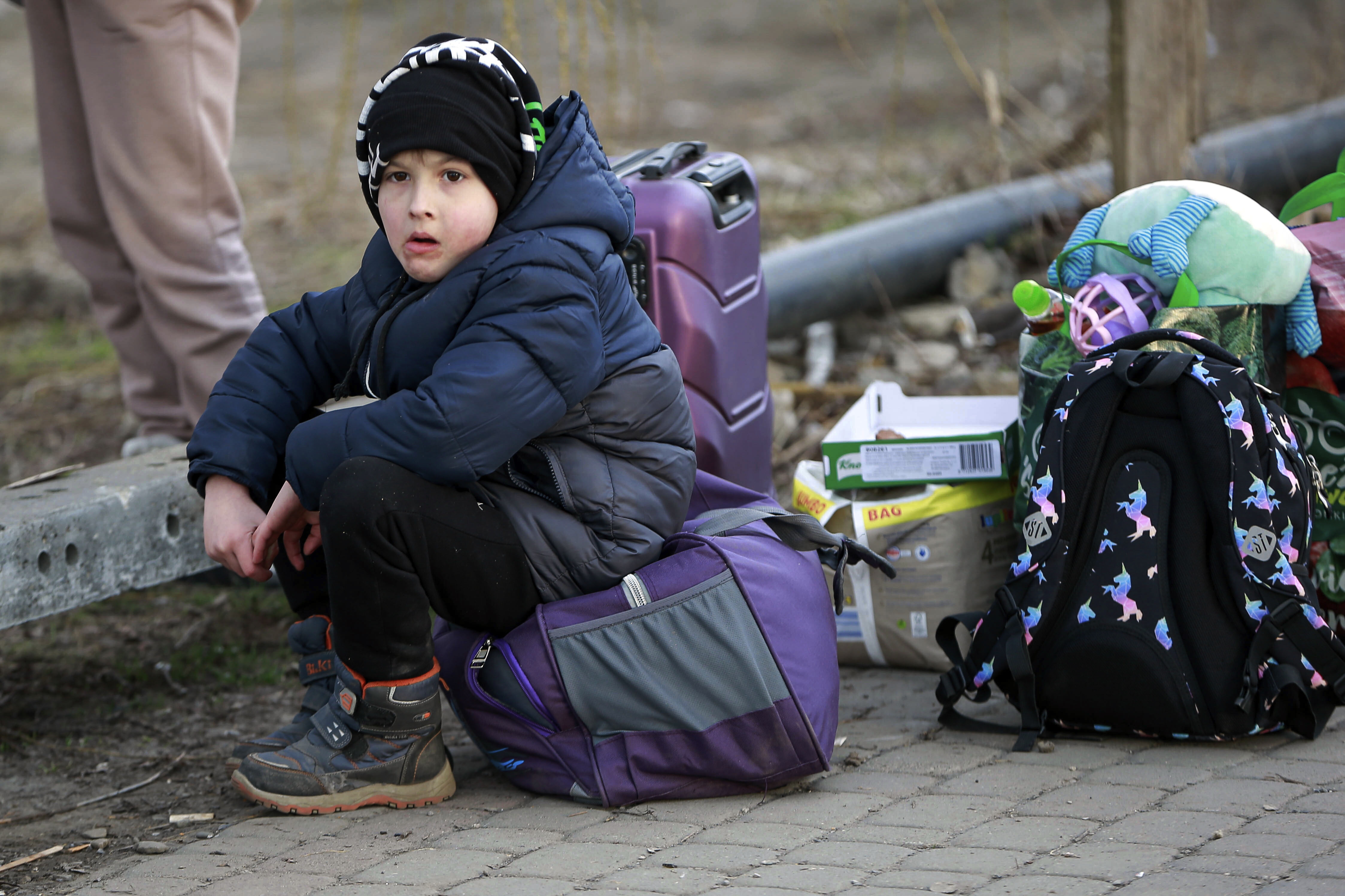 Ukranian refugee boy sits on top of his belongings as he arrived at the Medyka border crossing, Poland, Saturday, Feb. 26, 2022. (AP Photo/Visar Kryeziu)