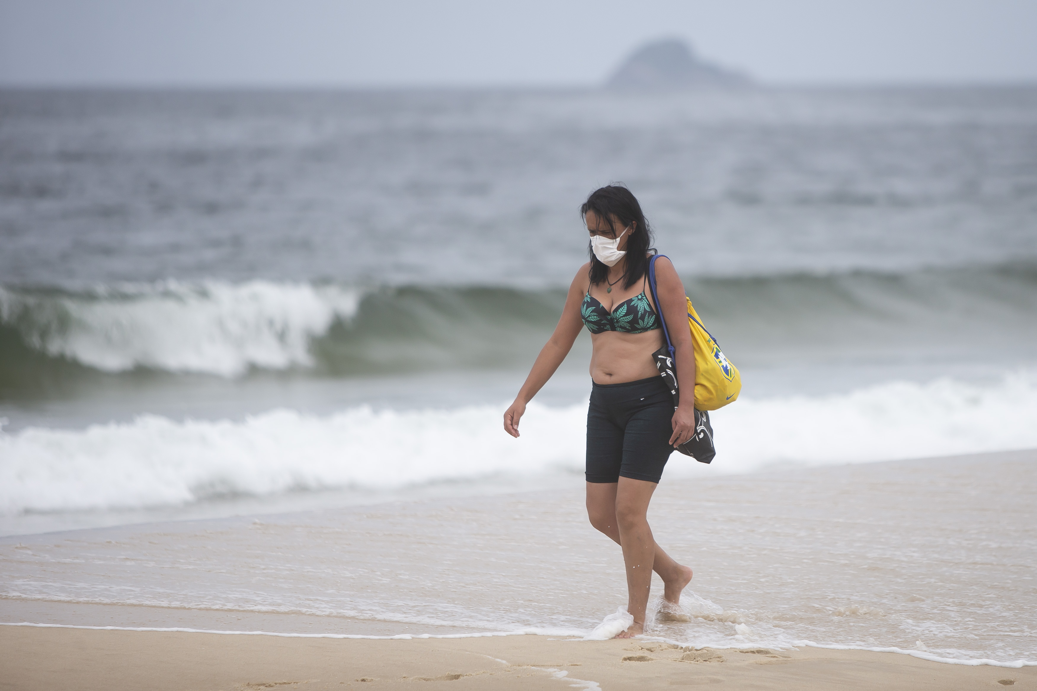 RIO DE JANEIRO, BRAZIL - MARCH 21: A beachgoer wearing a mask walks at Ipanema Beach during a lockdown aimed at stopping the spread of the (COVID-19) coronavirus pandemic.
