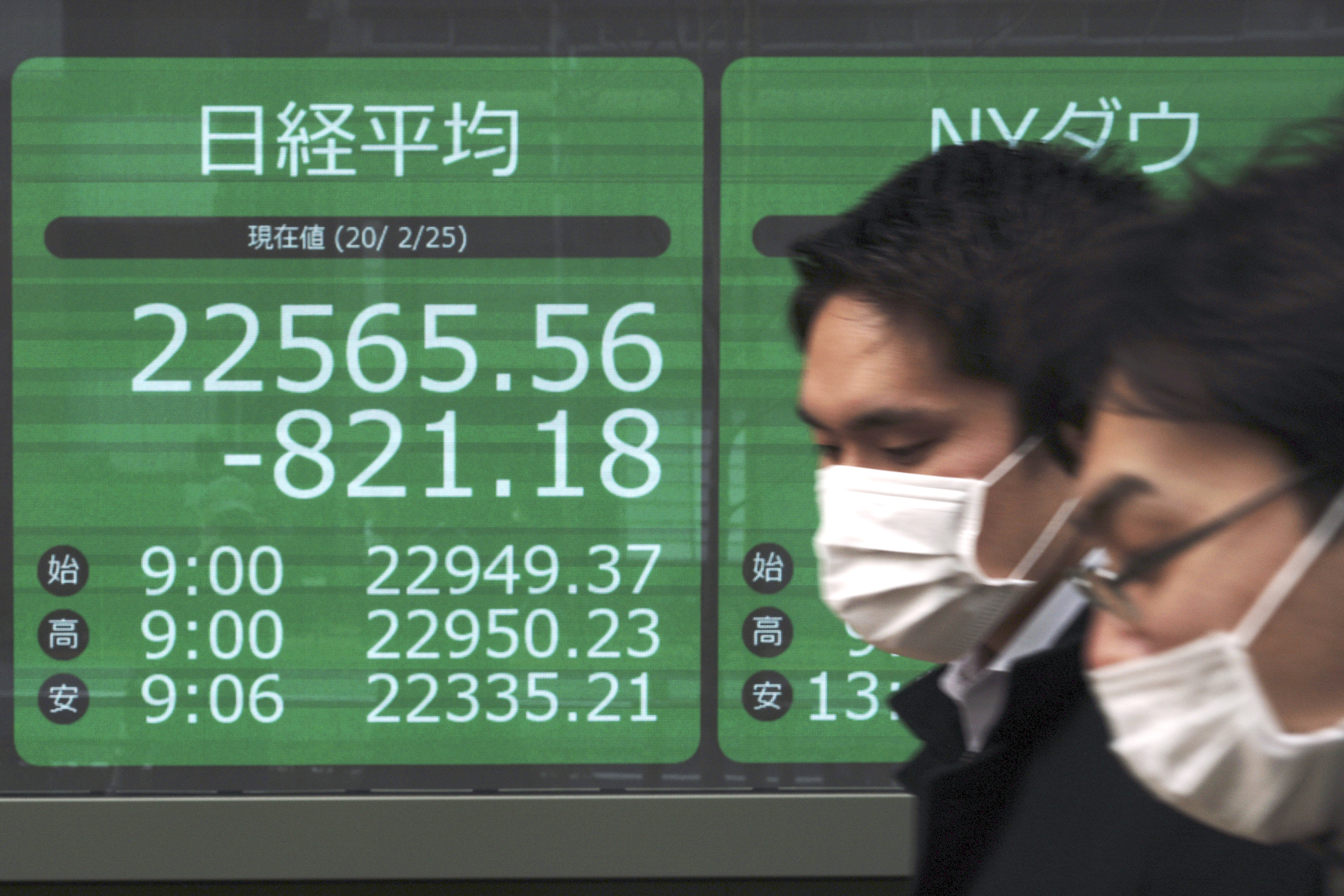 Men walk past an electronic stock board showing Japan's Nikkei 225 index at a securities firm in Tokyo.