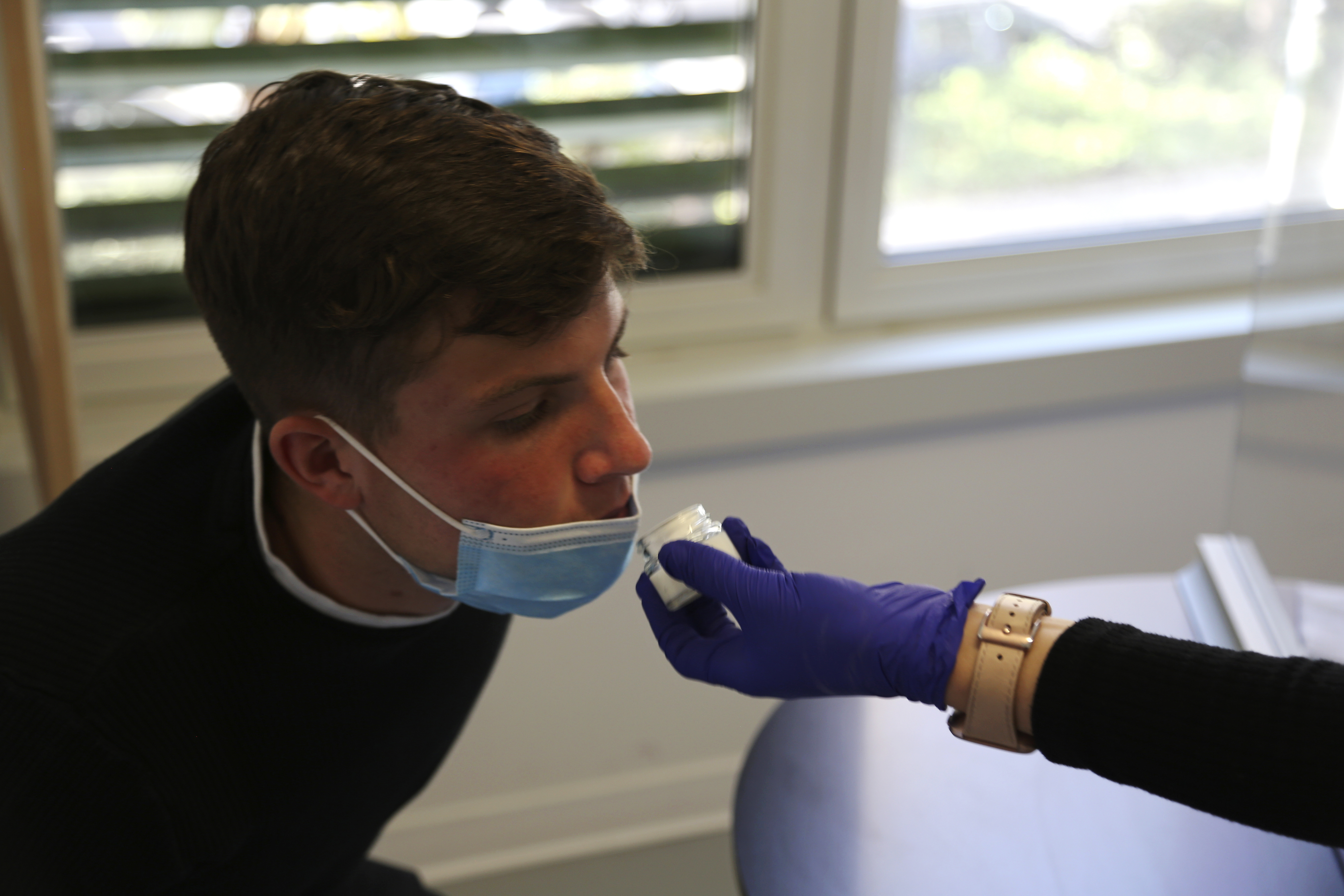 Evan Cesa, a patient, smells a small pot of fragrance during tests in a clinic in Nice, France, on Monday, Feb. 8, 2021. 