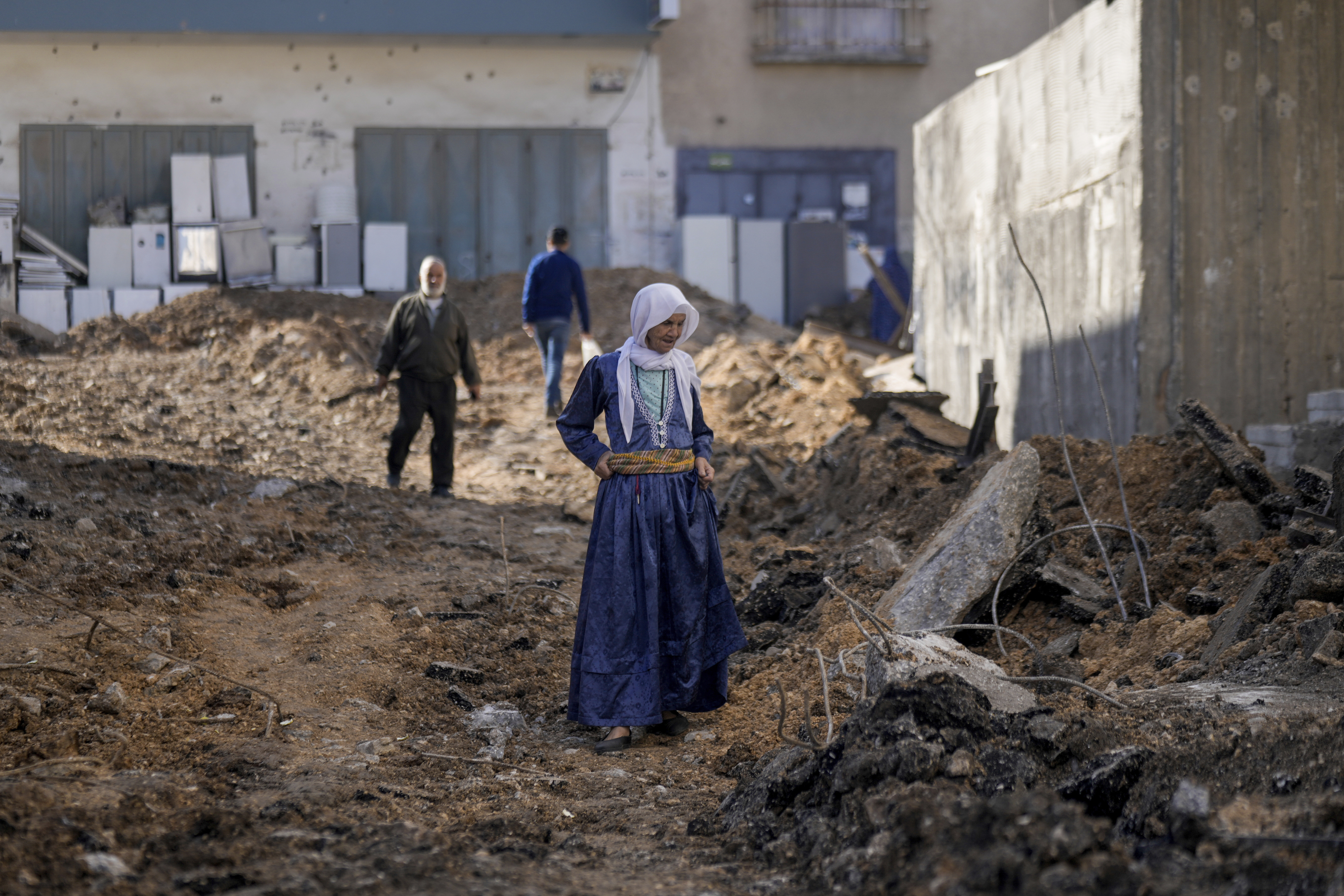 Palestinians walk on a damaged road following an Israeli military raid in Jenin refugee camp, West Bank, Friday, Nov. 17, 2023. 