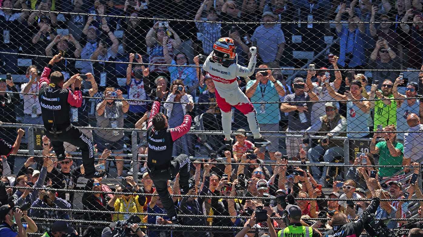 Helio Castroneves climbs the fence after winning the 105th running of the Indianapolis 500.