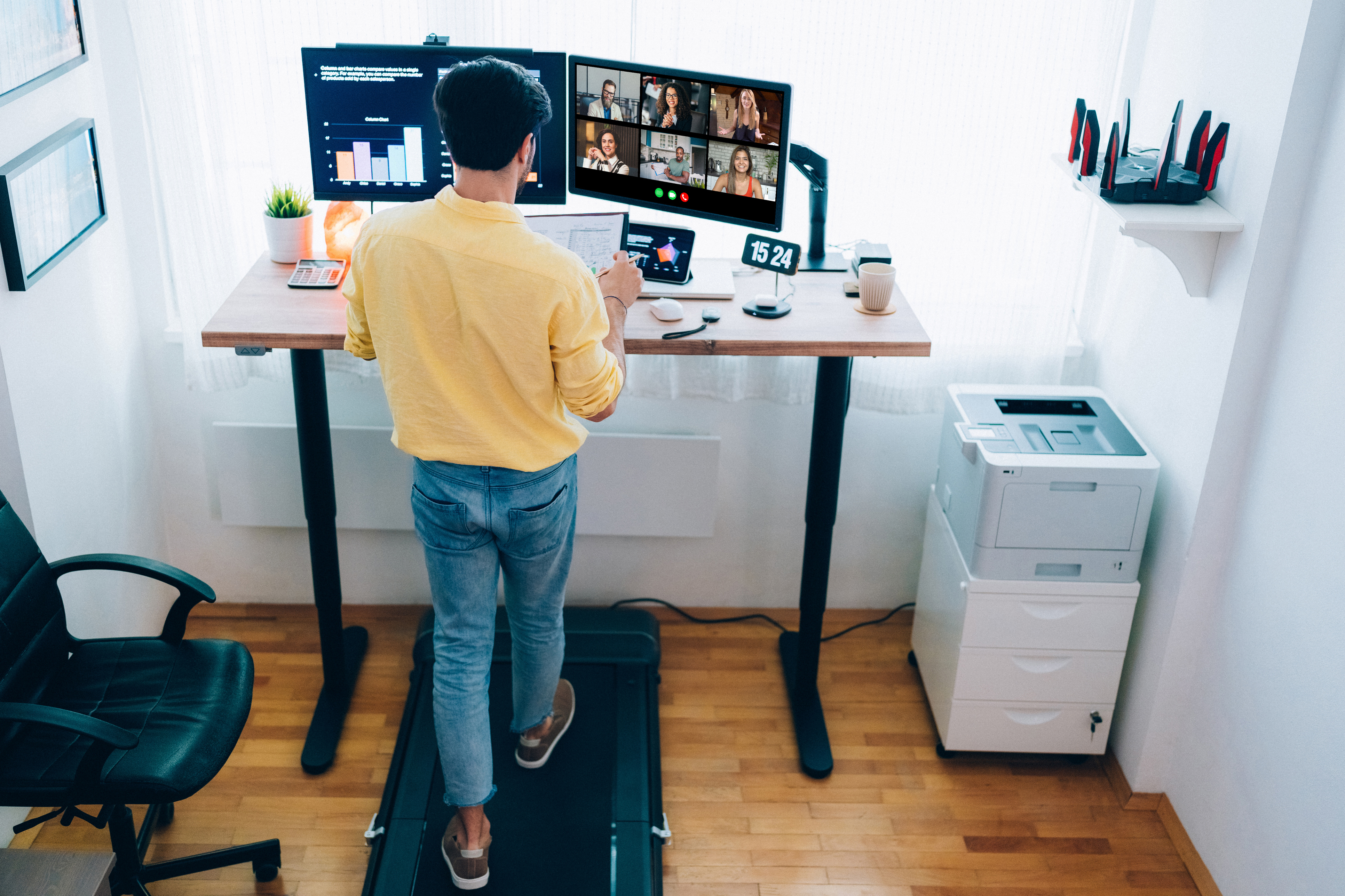 Man working from home at standing desk is walking on under desk treadmill