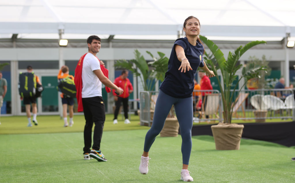 Carlos Alcaraz of Spain interacts as Emma Raducanu of Great Britain warms up.