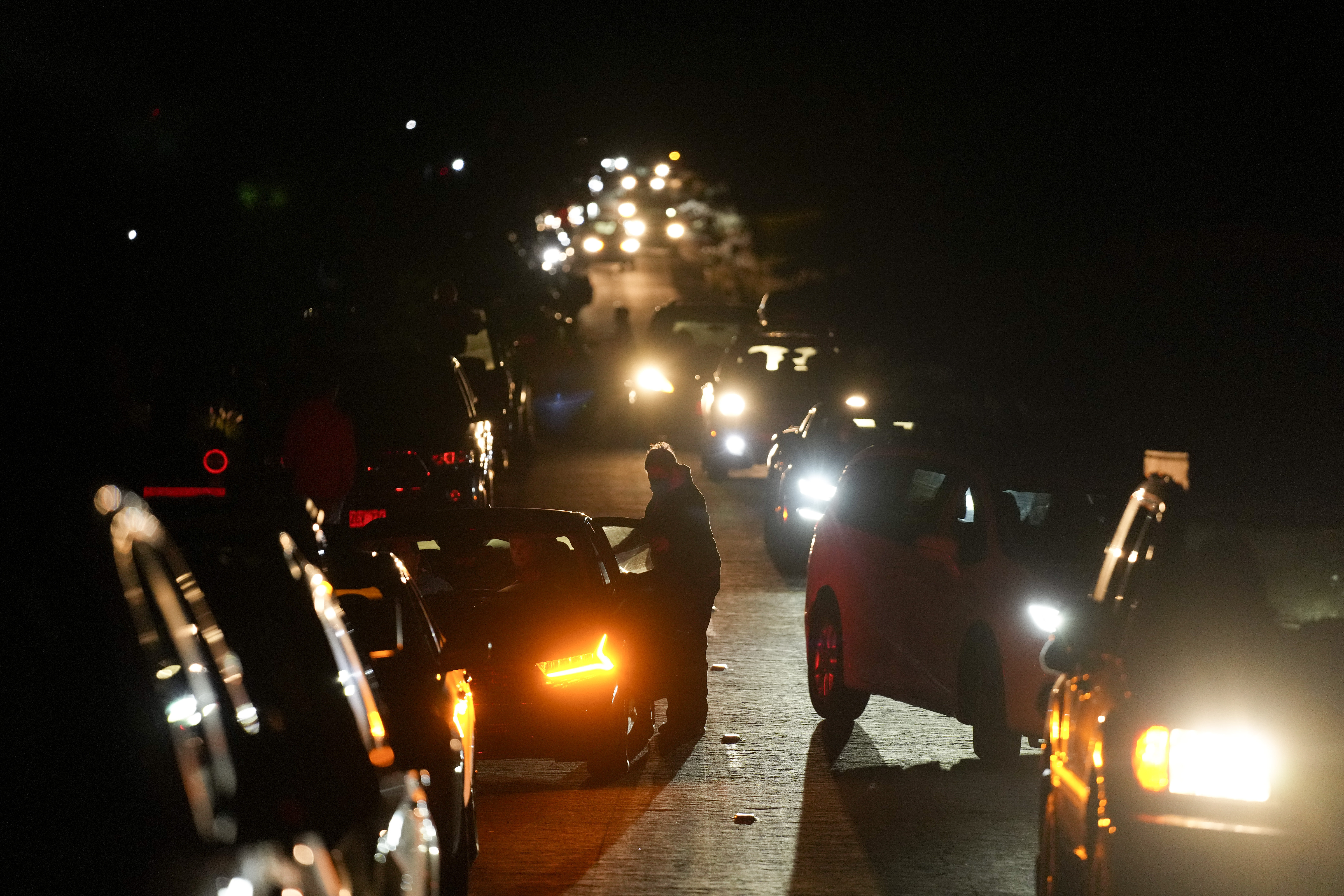 Motorists make their way along as people search for a vantage point of the erupting Mauna Loa volcano, Friday, Dec. 2, 2022, near Hilo, Hawaii.
