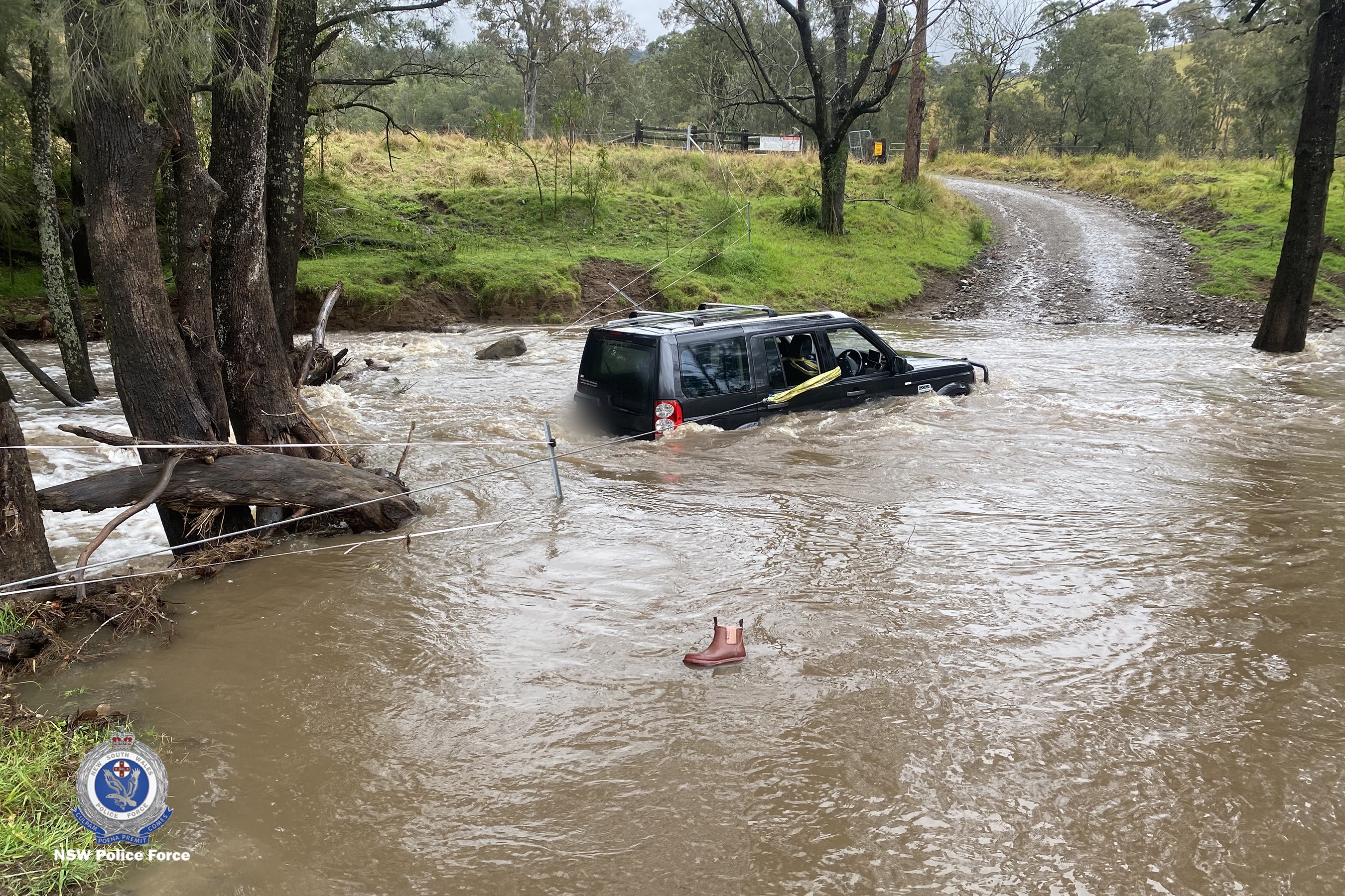 Three people rescued by police officer from car stuck in floodwaters in NSW Hunter region.