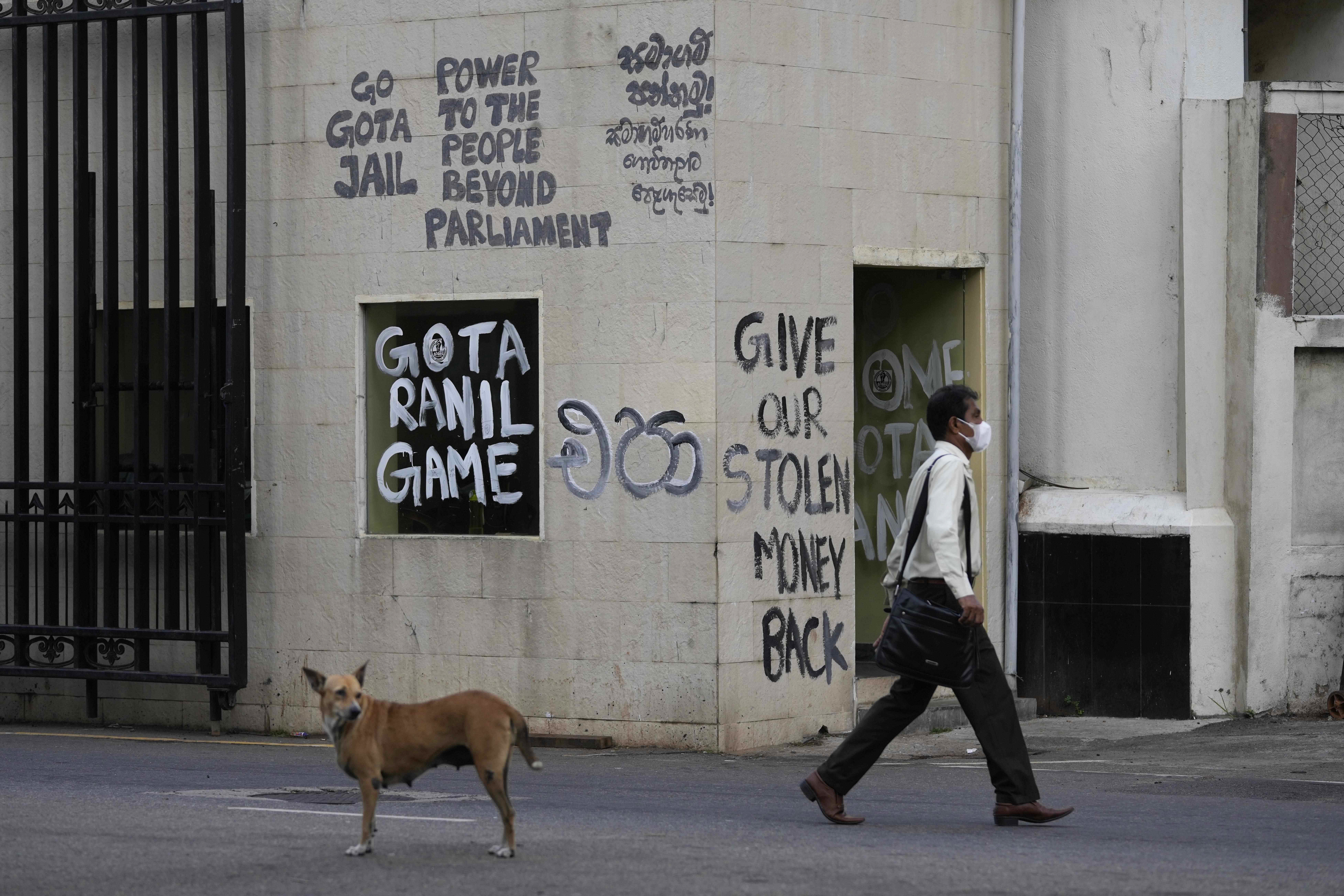 A man walks past a vandalised security point outside president's official residence in Colombo, Sri Lanka, Friday, July 15, 2022. 