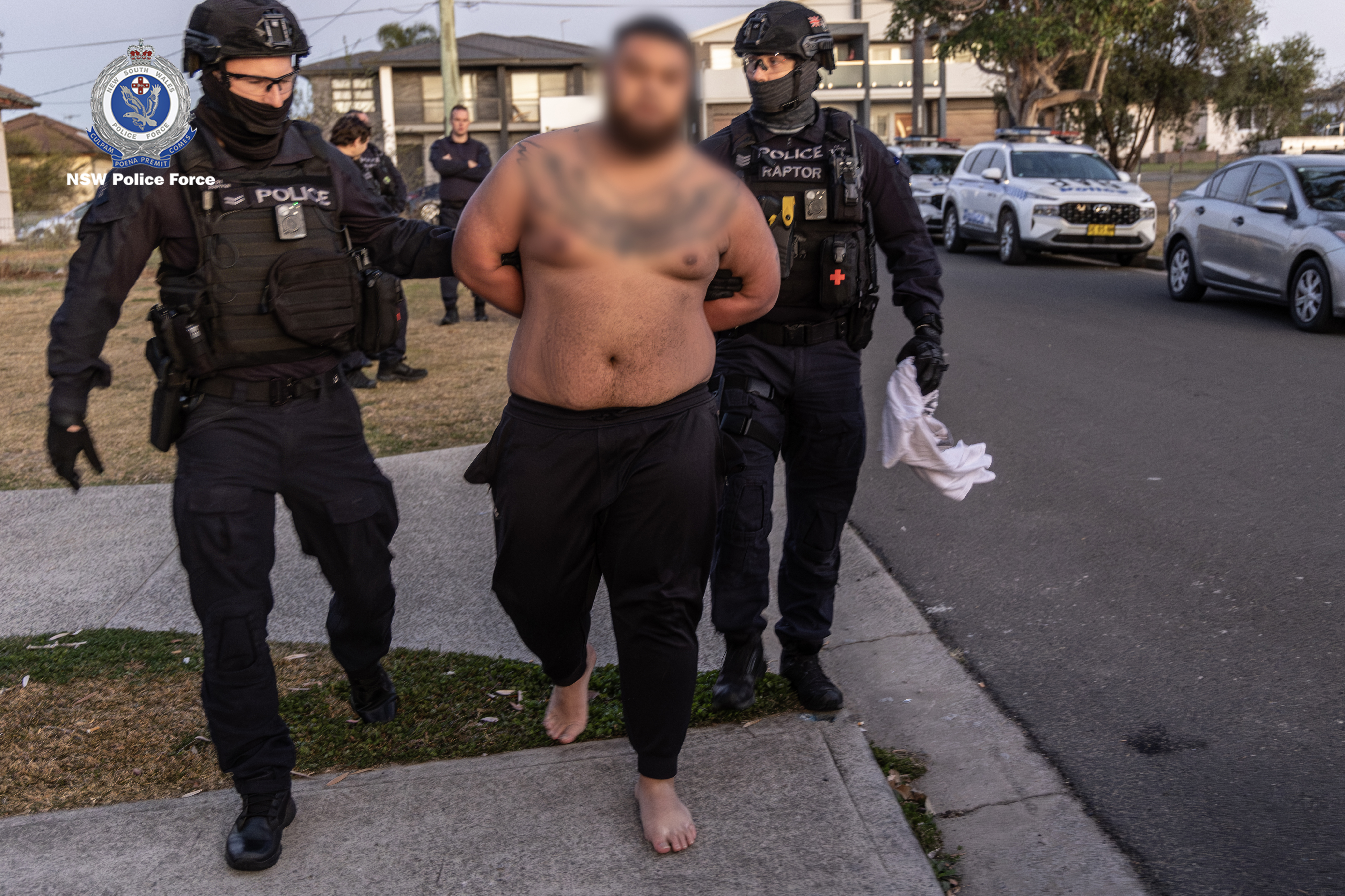 A man has been charged for posing in a photo with a toddler holding guns the day before a man was executed in a shooting gangland murder.