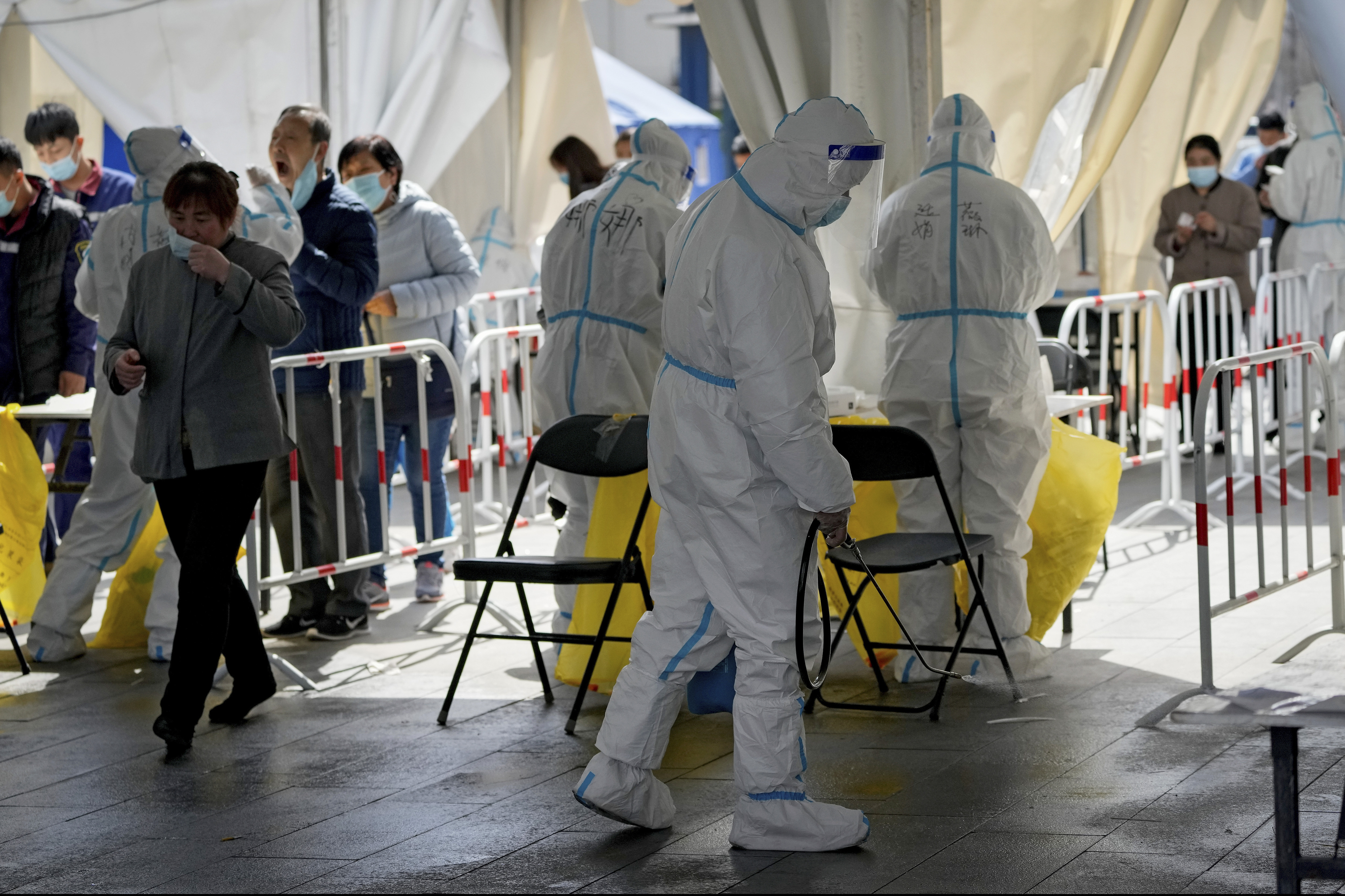 A health worker sprays disinfectant as residents get a throat swab at a coronavirus testing site after the Disneyland in Shanghai was closed.