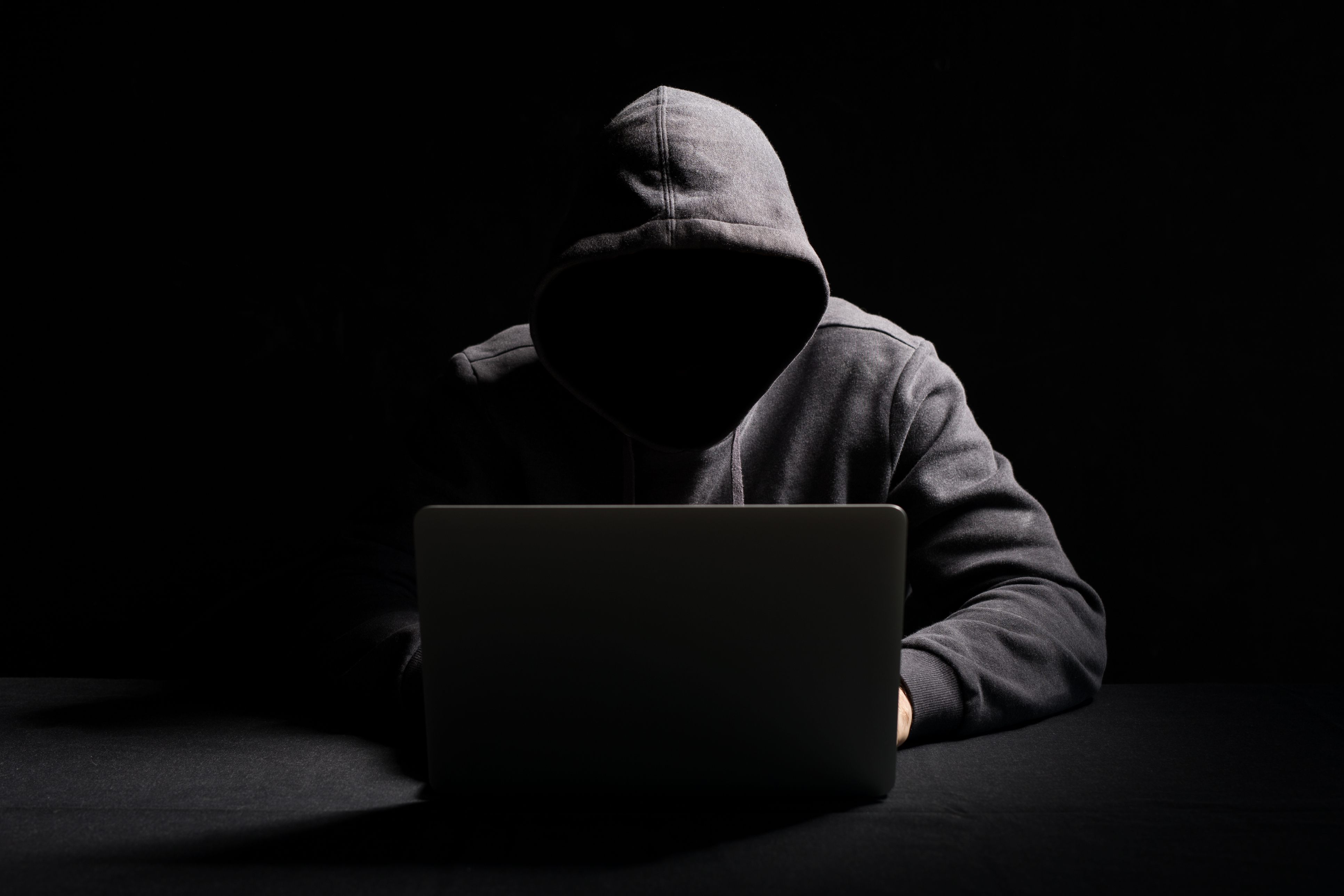 Hacker scammer dark hooded laptop computer