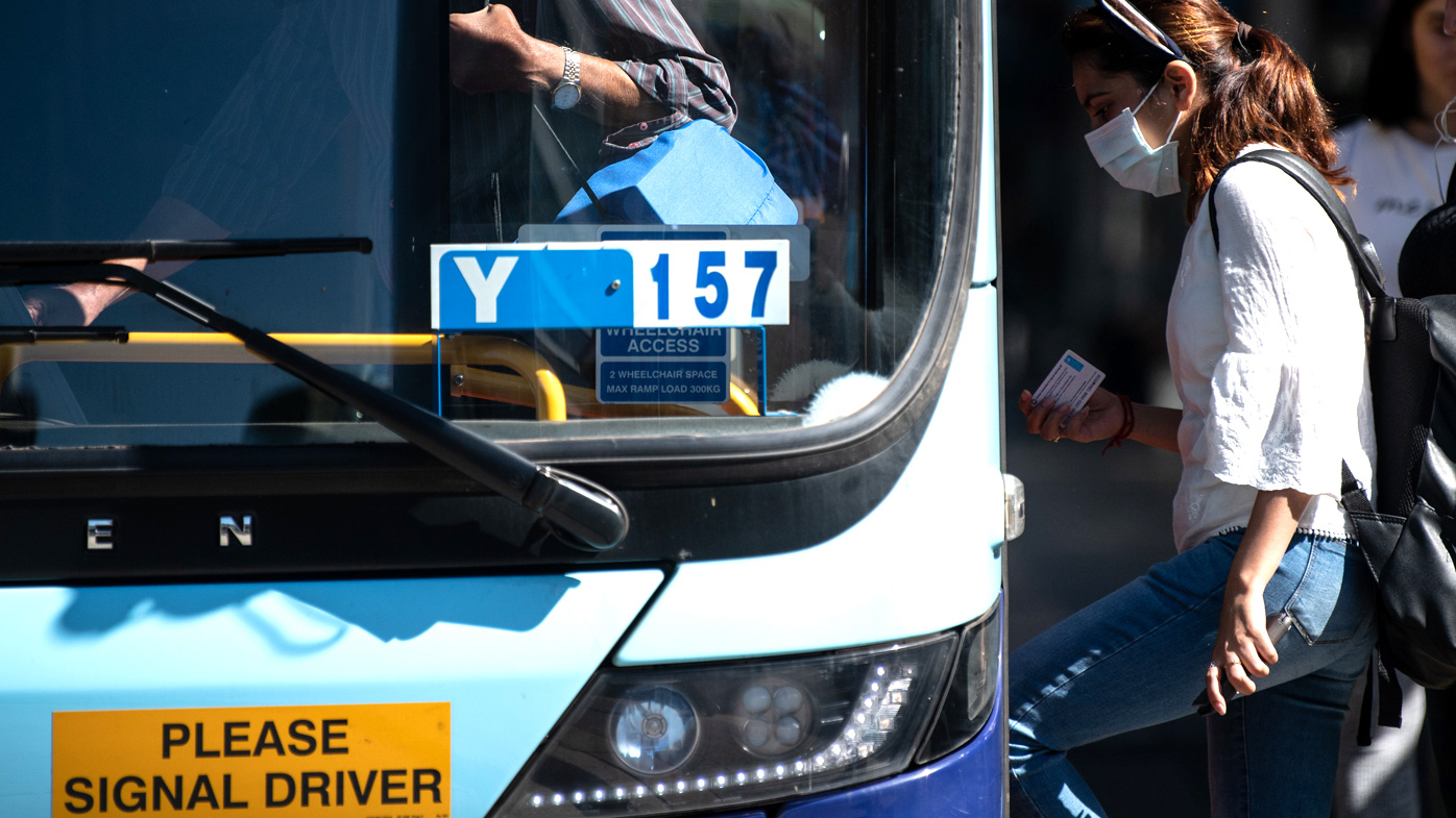 A woman wearing a protective face mask boards a bus in Sydney
