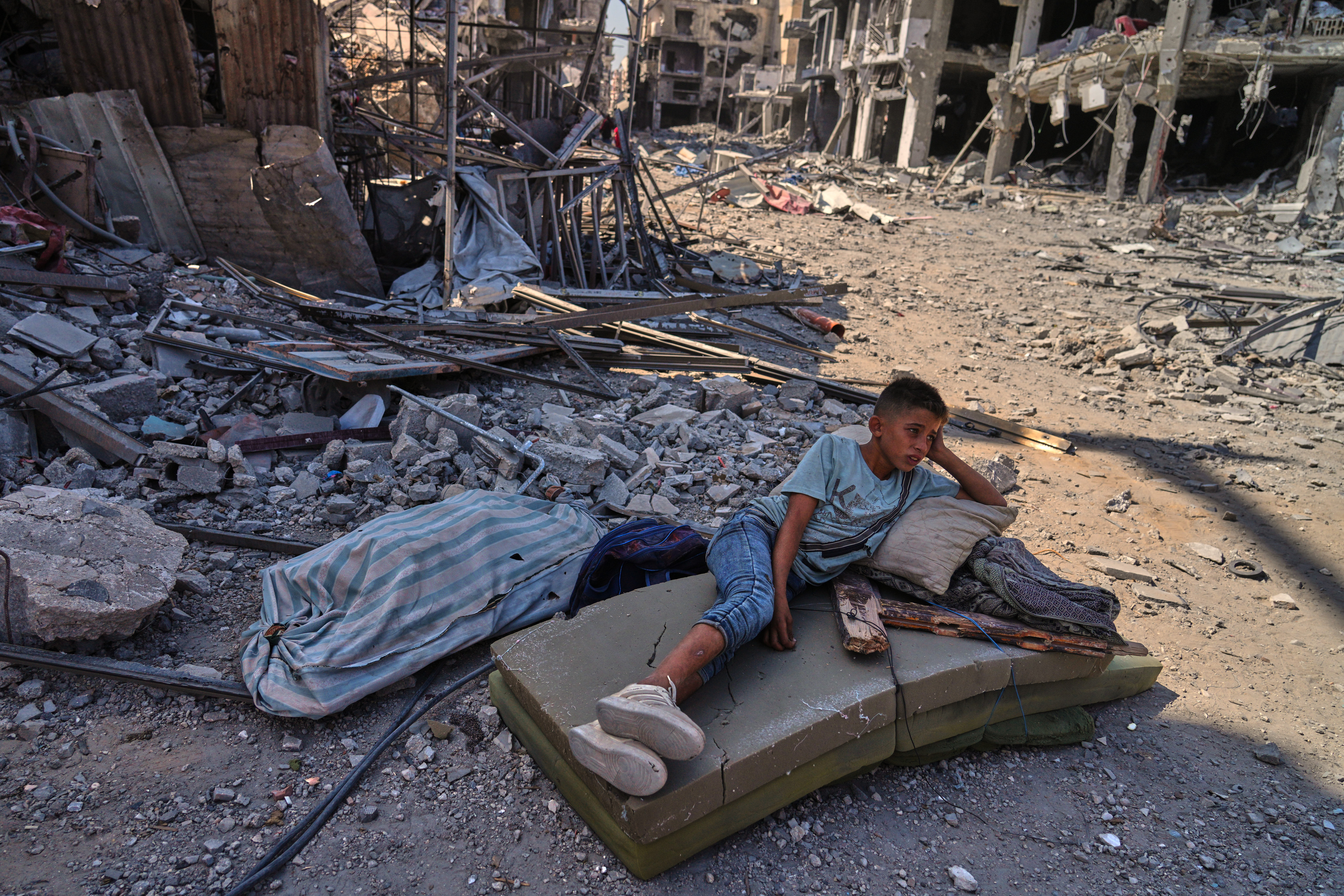 A Palestinian boy lies on a mattress amid the rubble 