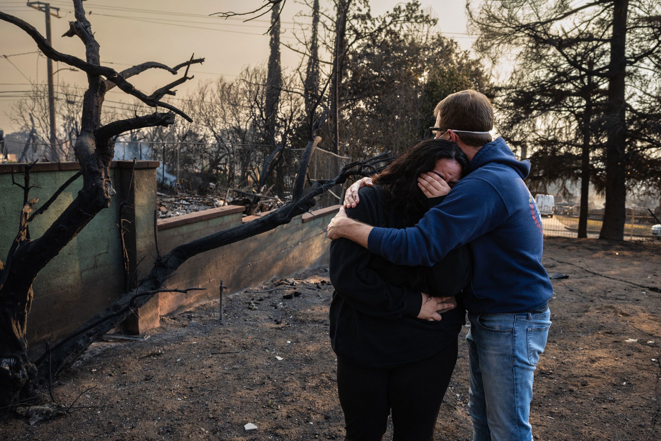 Un hombre consuela a su hija junto a las ruinas carbonizadas de la casa familiar que se quemó en el incendio Eaton en Altadena, California.