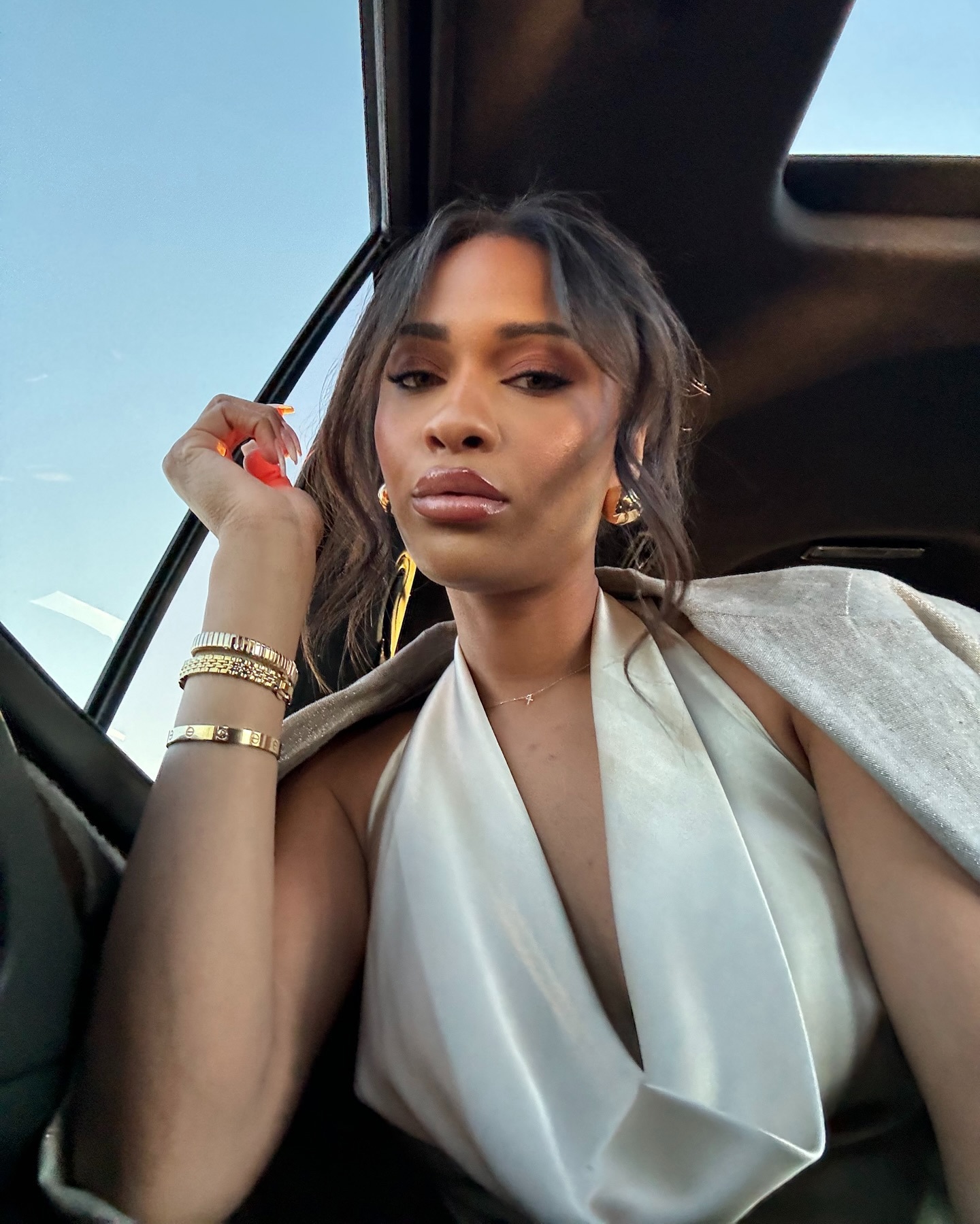 Ayan Broomfield poses in gold jewellery and a white outfit.