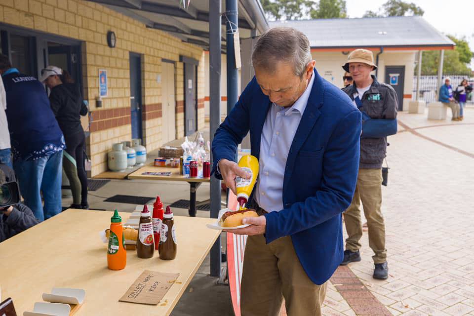 Western Australian Premier Roger Cook puts mustard on a sausage sandwich at a polling booth as the Rockingham by-election is underway.