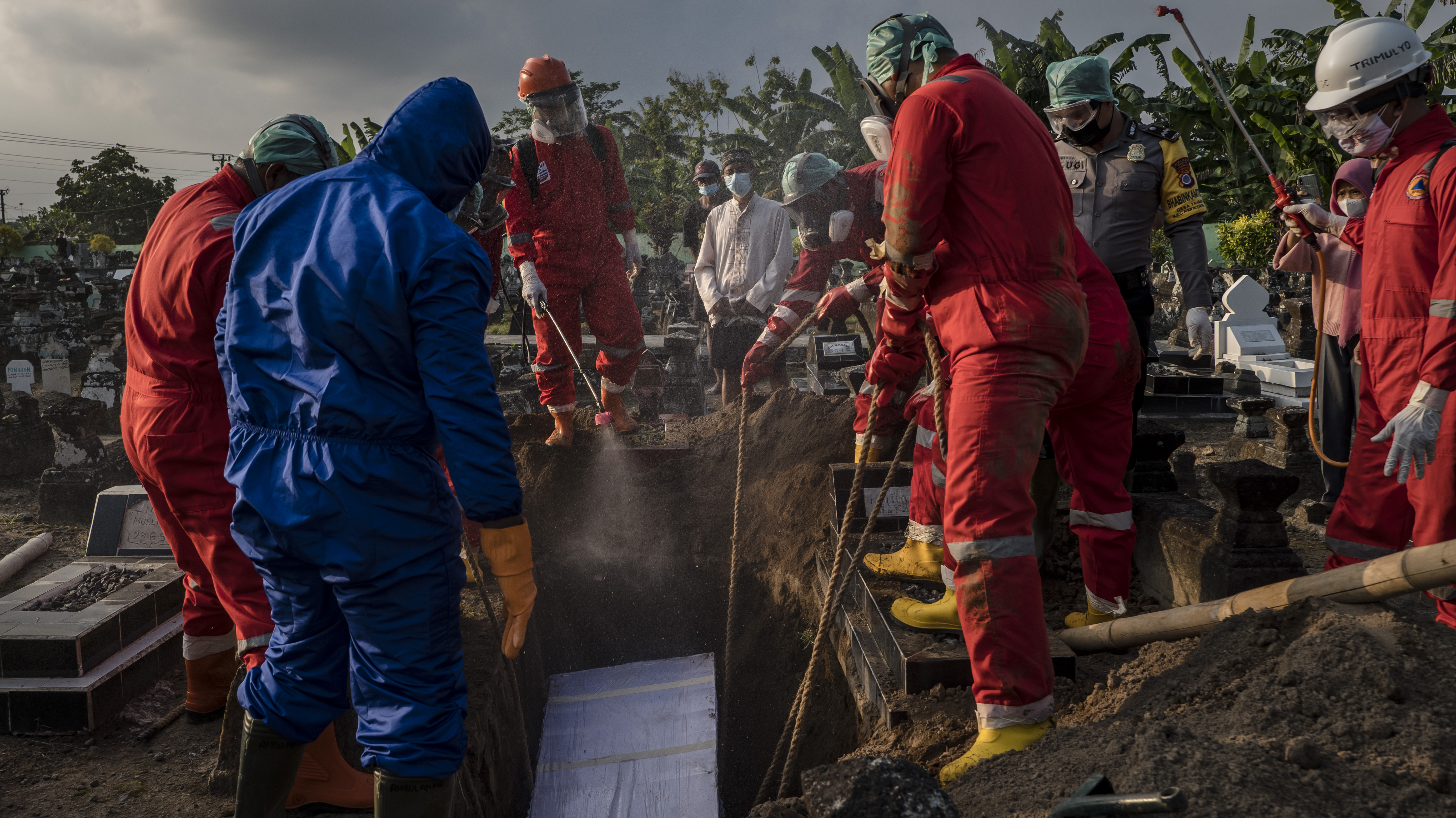 Volunteers conduct a burial the body of a woman suspected to have died from COVID-19 while isolating at home in Yogyakarta, Indonesia. 