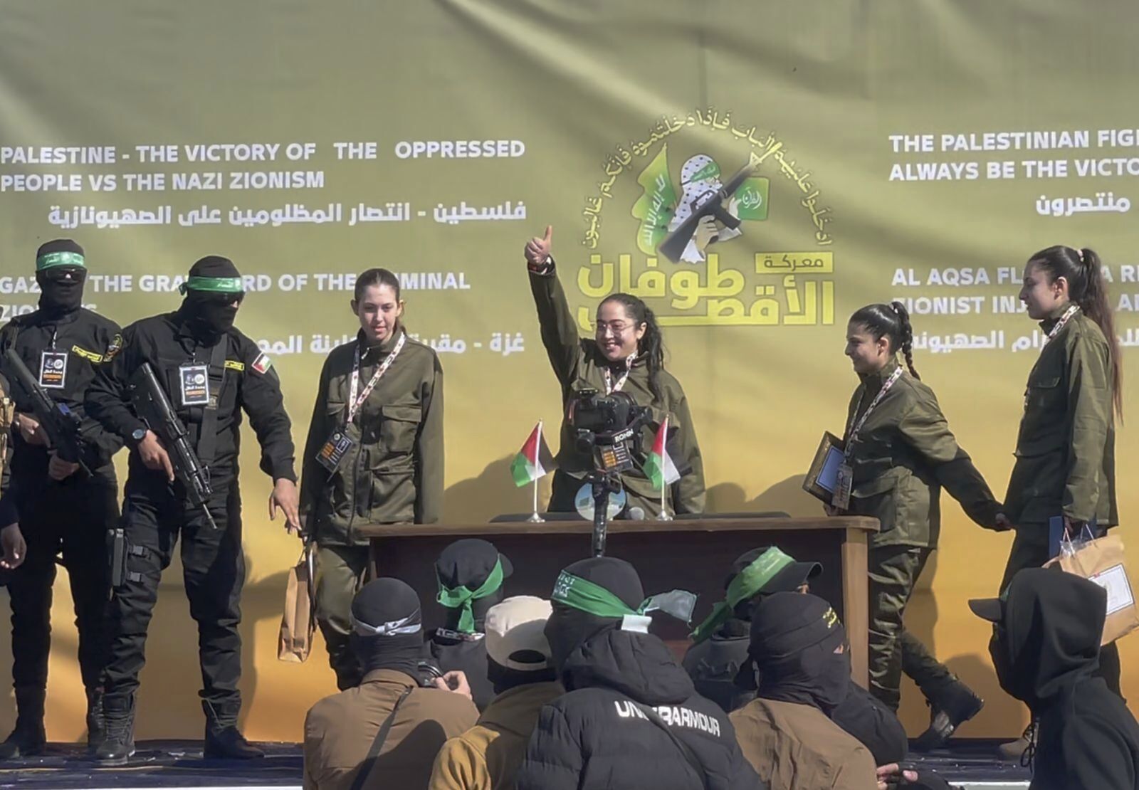 Israeli female soldier hostages wave at a Palestinian crowd 