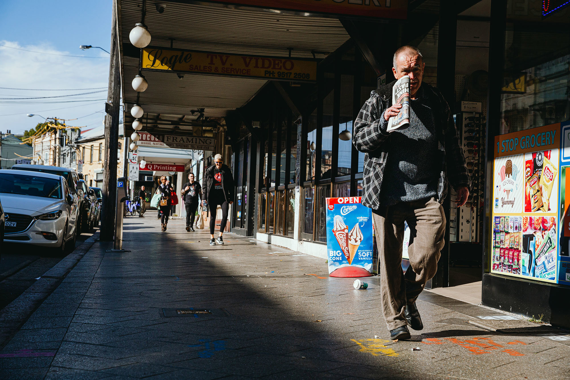 A man walks down the street past a row of shops