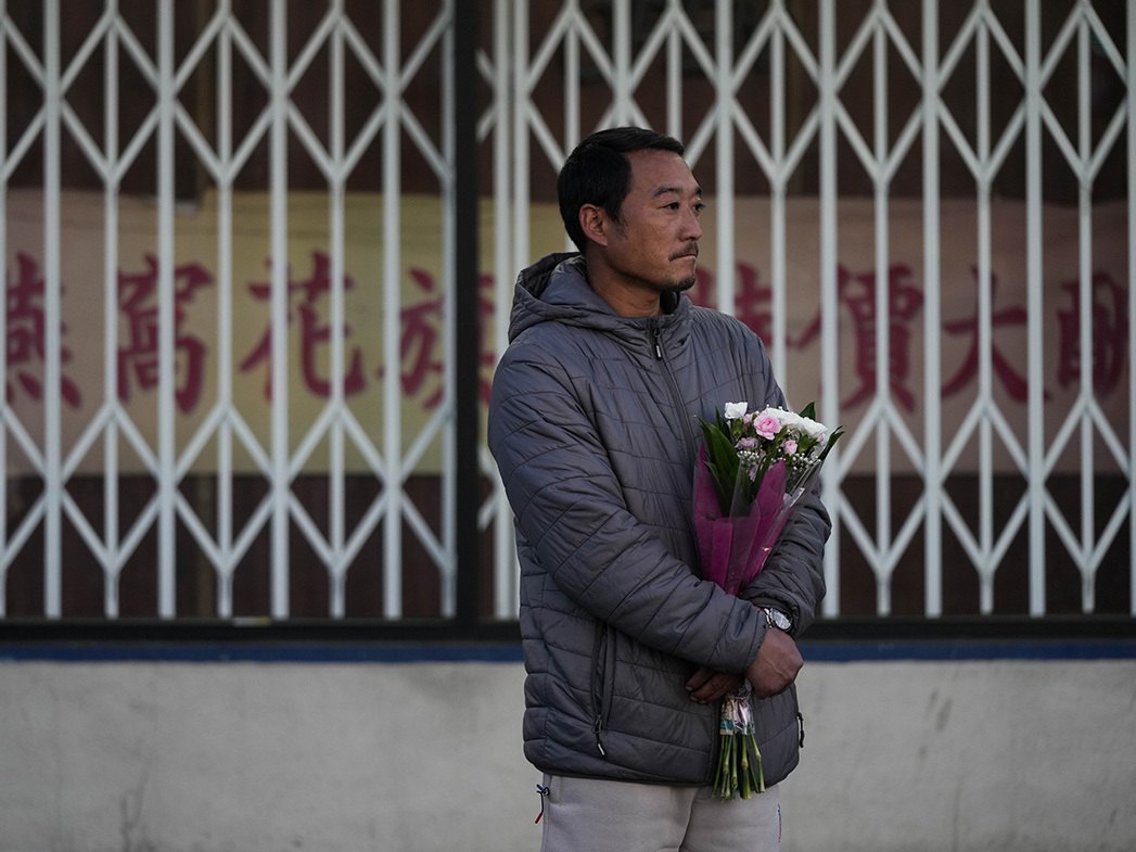 Hunter Zhao, 41, holds flowers to honor the victims killed in Saturday's ballroom dance studio shooting in Monterey Park, California.