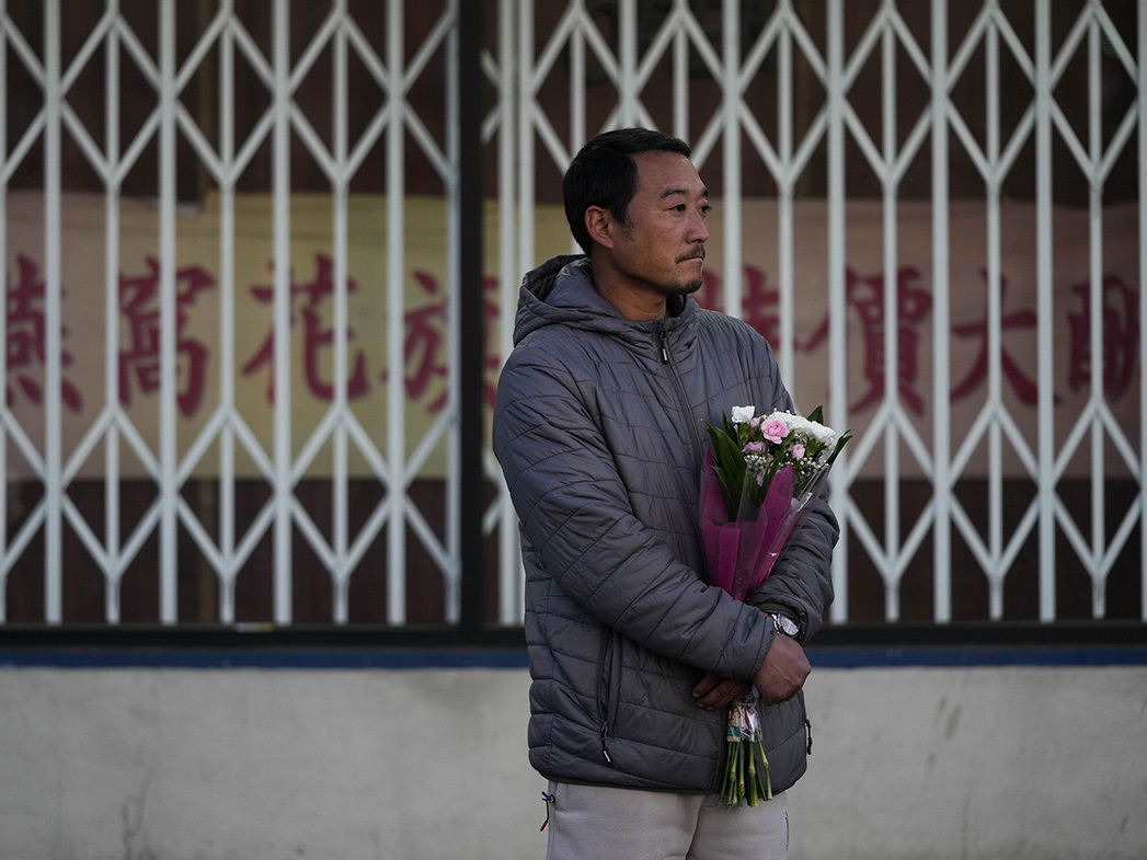 Hunter Zhao, de 41 años, sostiene flores en honor a las víctimas asesinadas en el tiroteo en el estudio de baile de salón del sábado en Monterey Park, California.