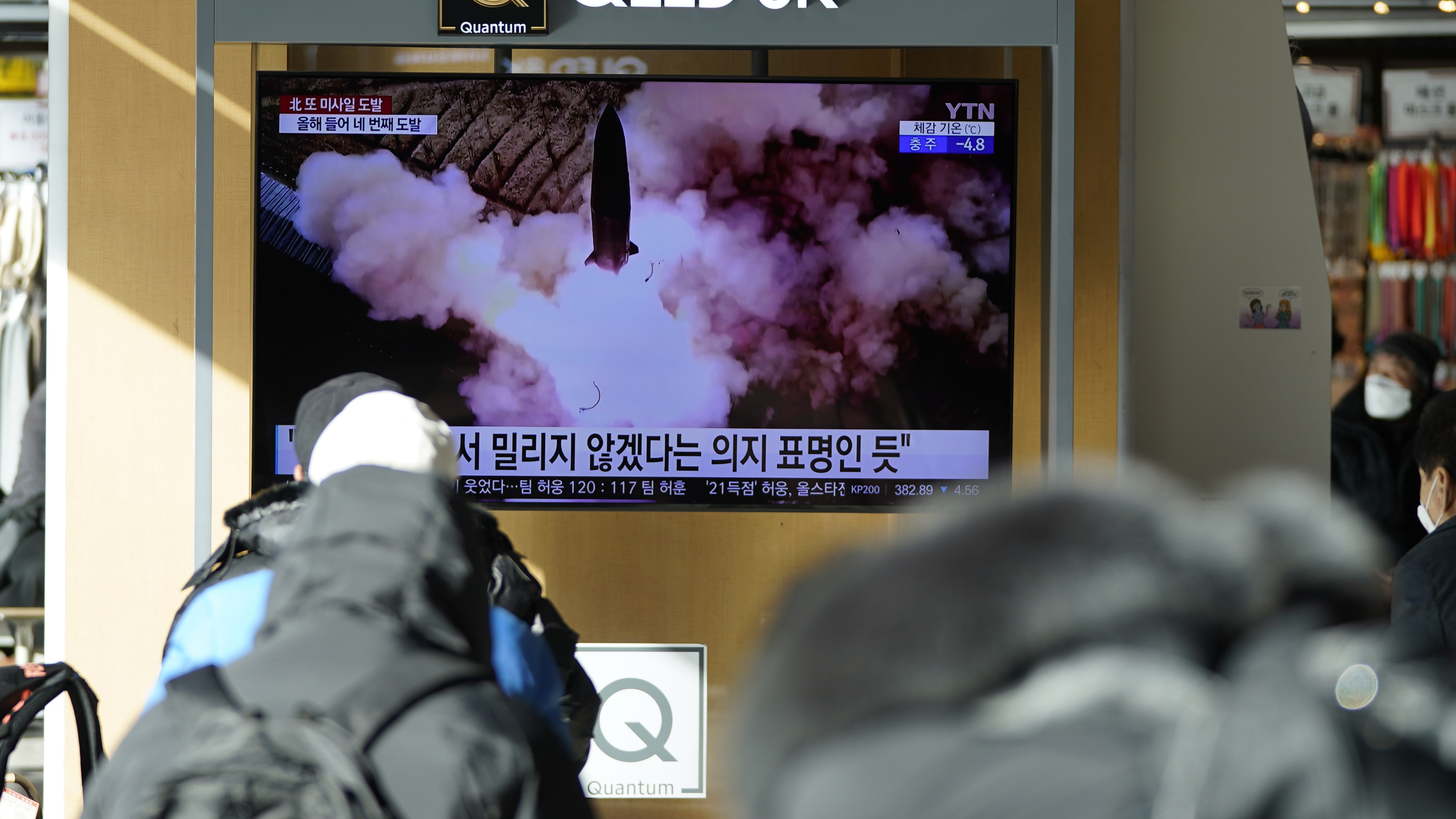 People watch a TV screen showing a news program reporting about North Korea's missile launch.