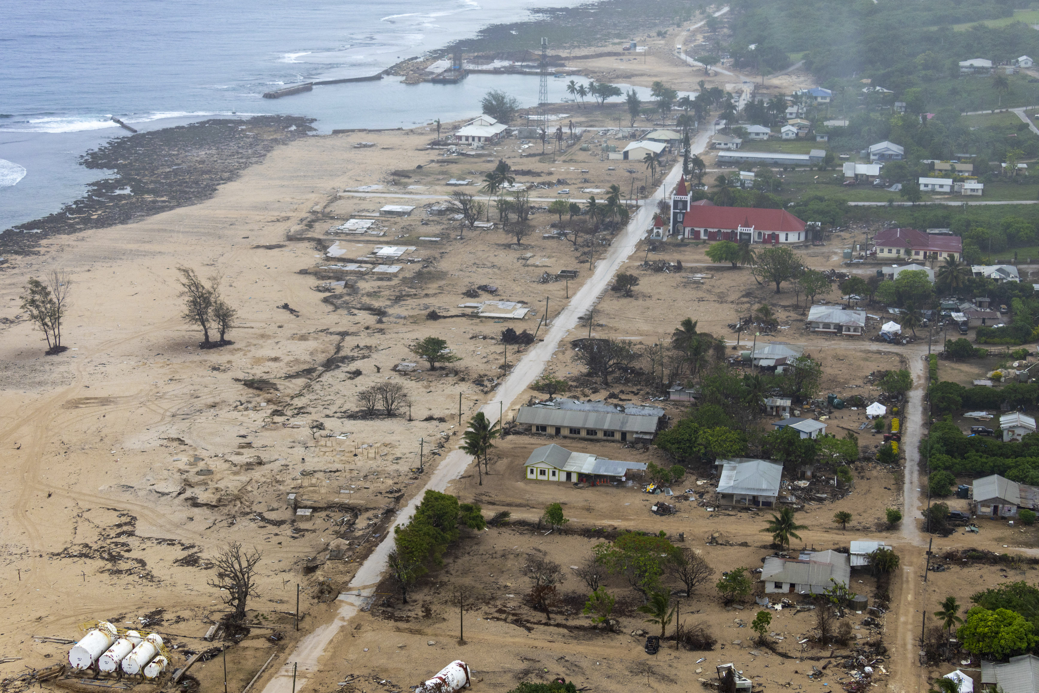 In this photo supplied by the Royal Australian Navy, an Australian Defence Force MRH-90 Taipan helicopter provides aerial reconnaissance of Eua Island in Tonga  on Feb. 21, 2022. Three months on from a devastating volcano and tsunami in Tonga, the AP checks in on how the island nation is recovering. The bill from the tsunami is estimated at some $90 million and GDP is expected to fall by more than 7% this year. The cleanup has been hindered by an internet outage caused by the tsunami and the nat